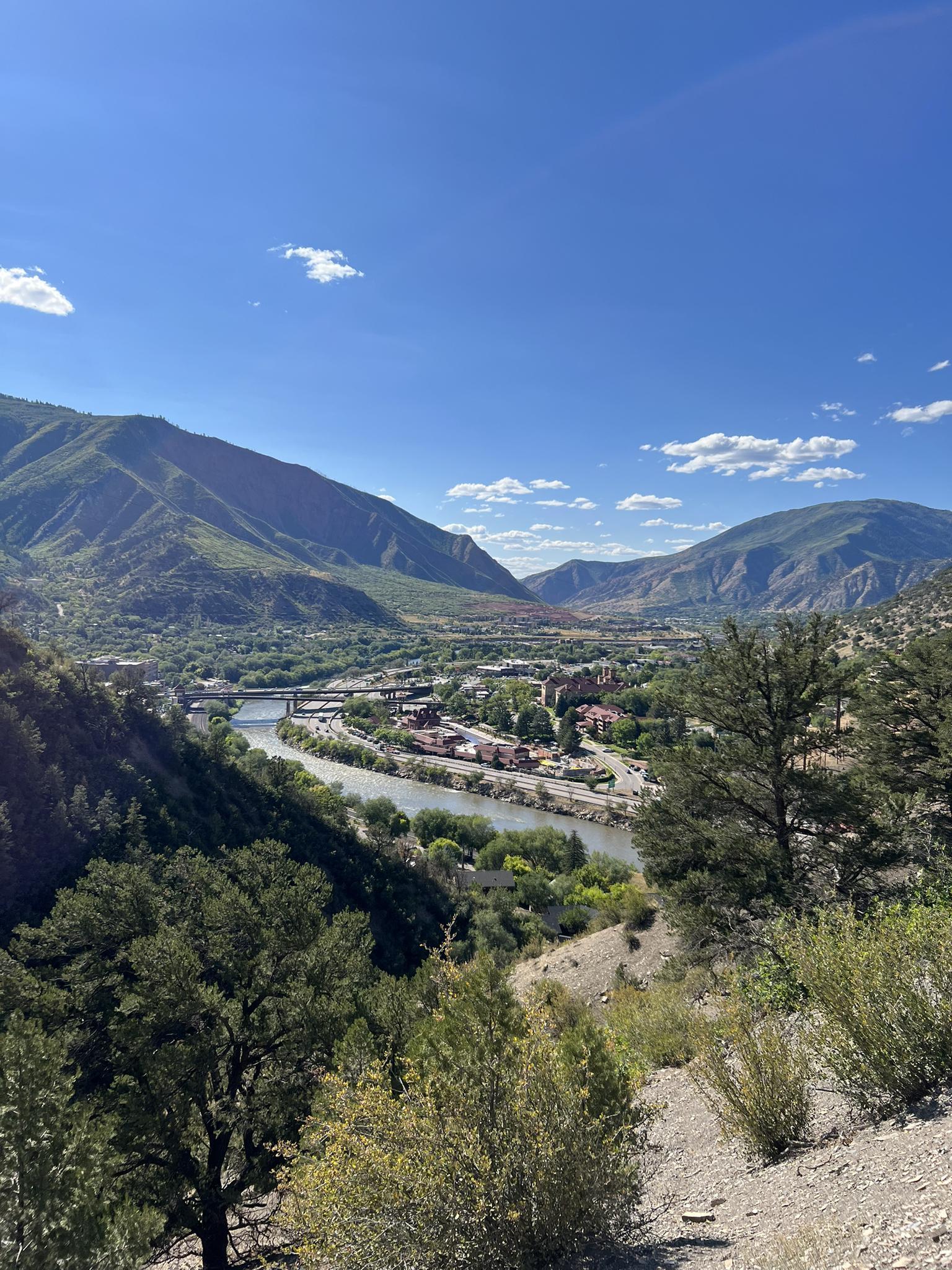 Panoramic view of a river flowing through a town nestled in a mountain valley.