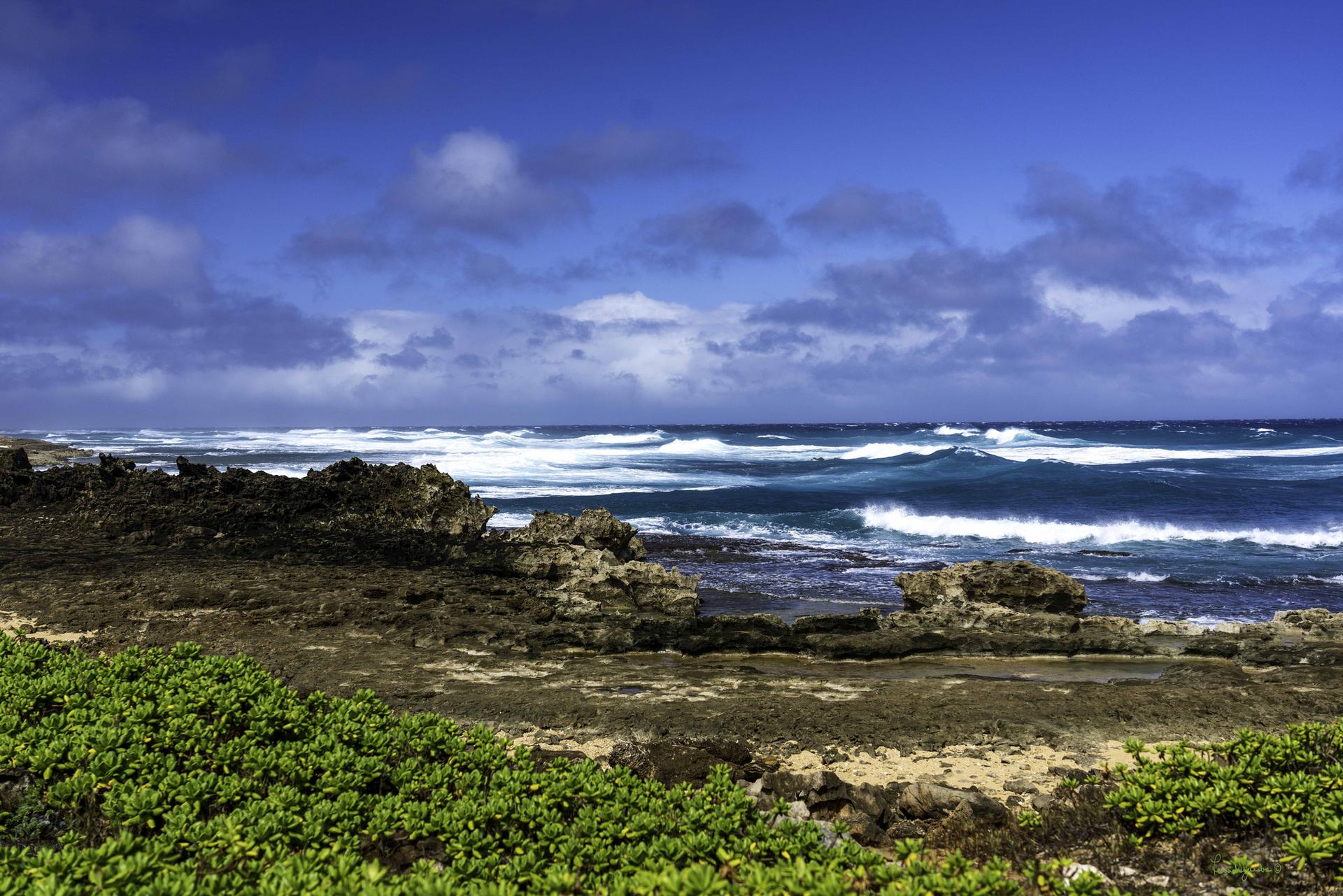 Rocky coastline with crashing waves under a dramatic, cloudy blue sky.