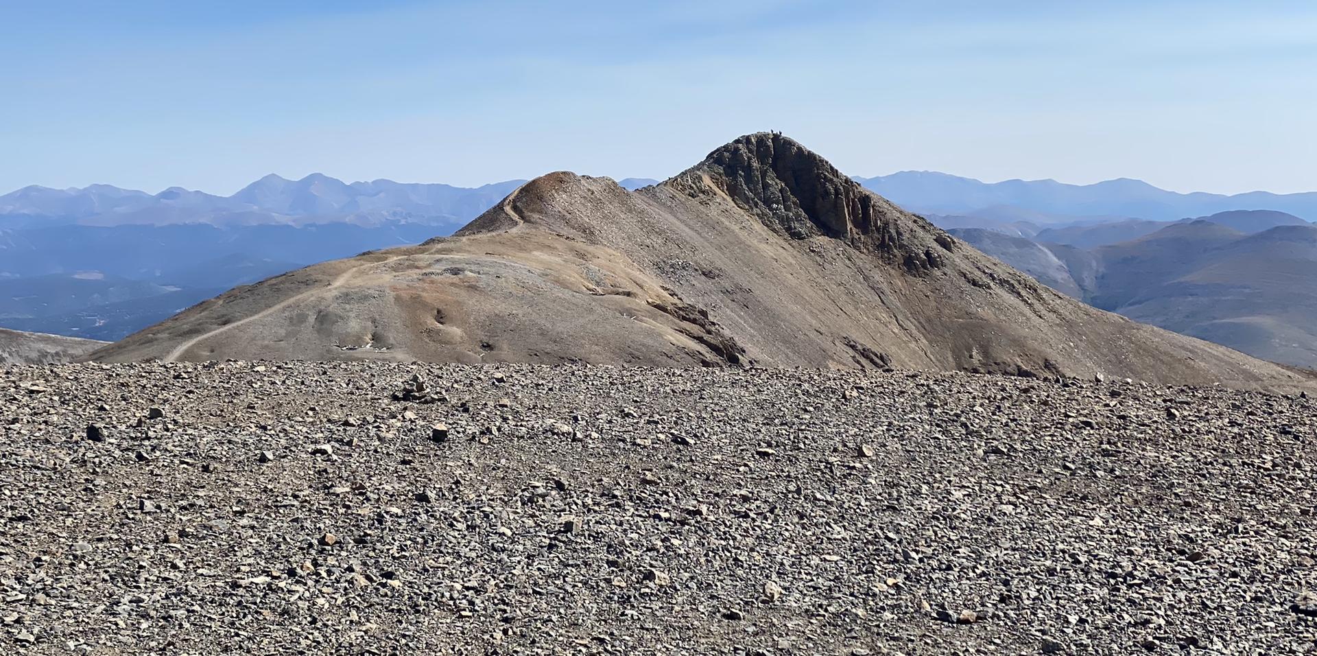 Distant rocky mountain peak beyond a vast, flat, gravelly foreground.