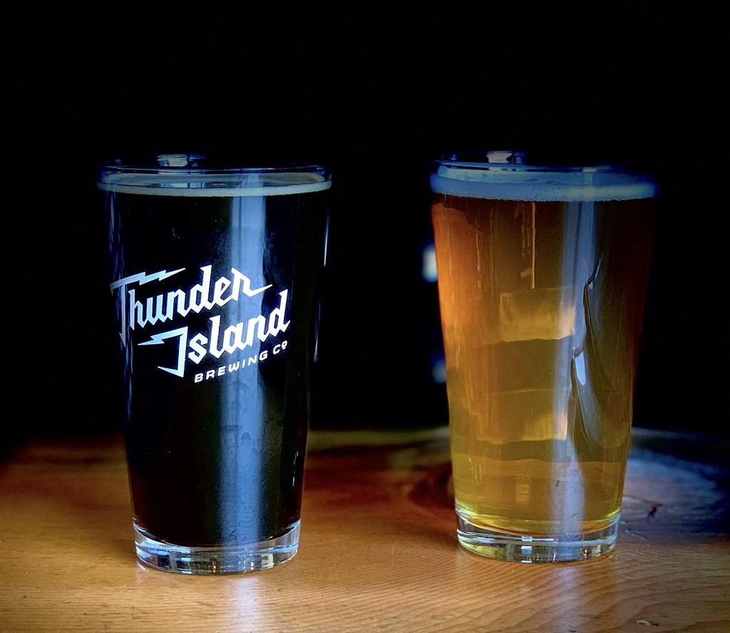 Two glasses of beer, one dark, one light, on a wooden surface.