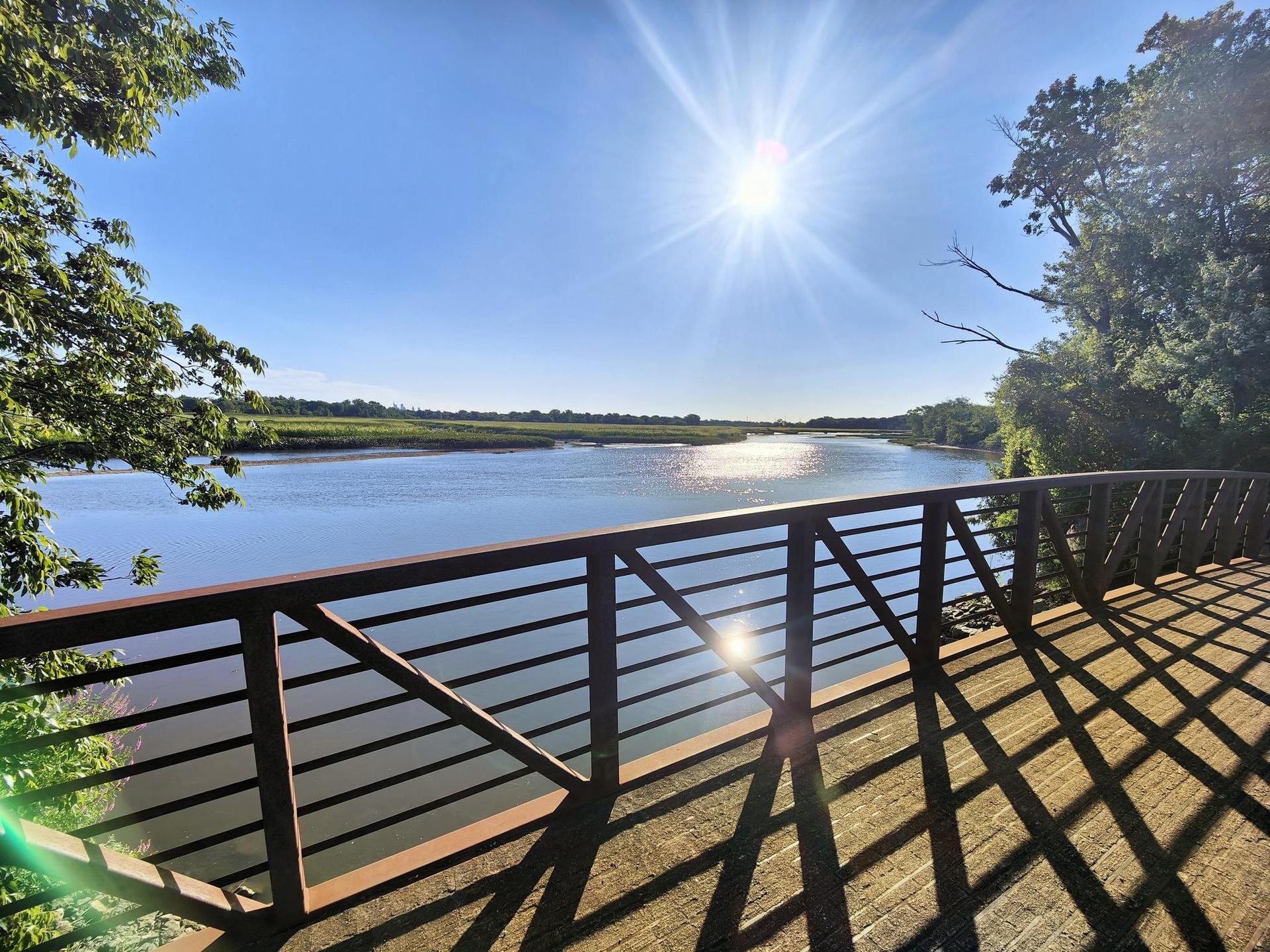 Sunny view from a wooden bridge over a wide river.
