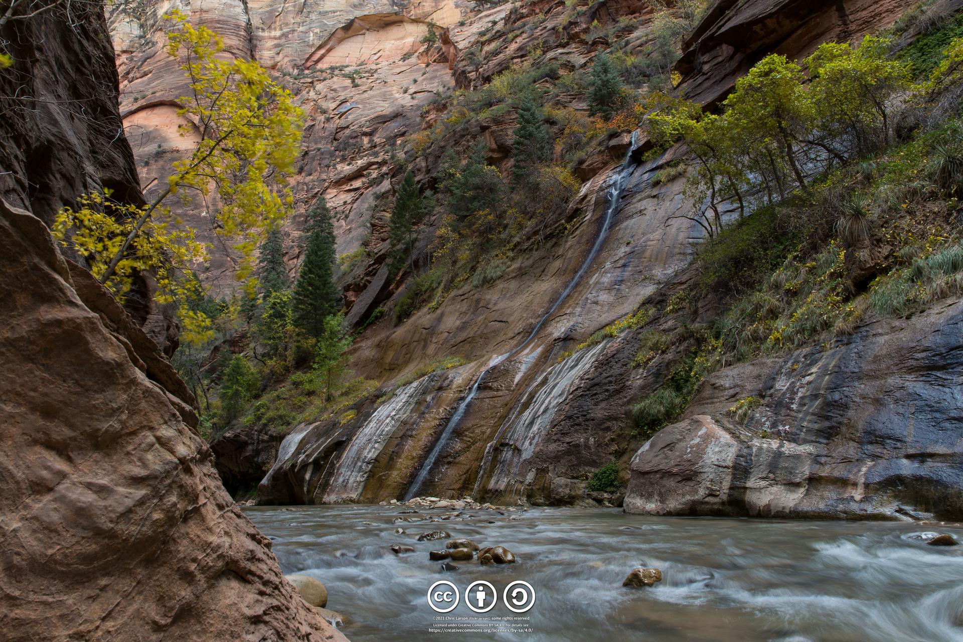 River flows past textured canyon walls with multiple small waterfalls.