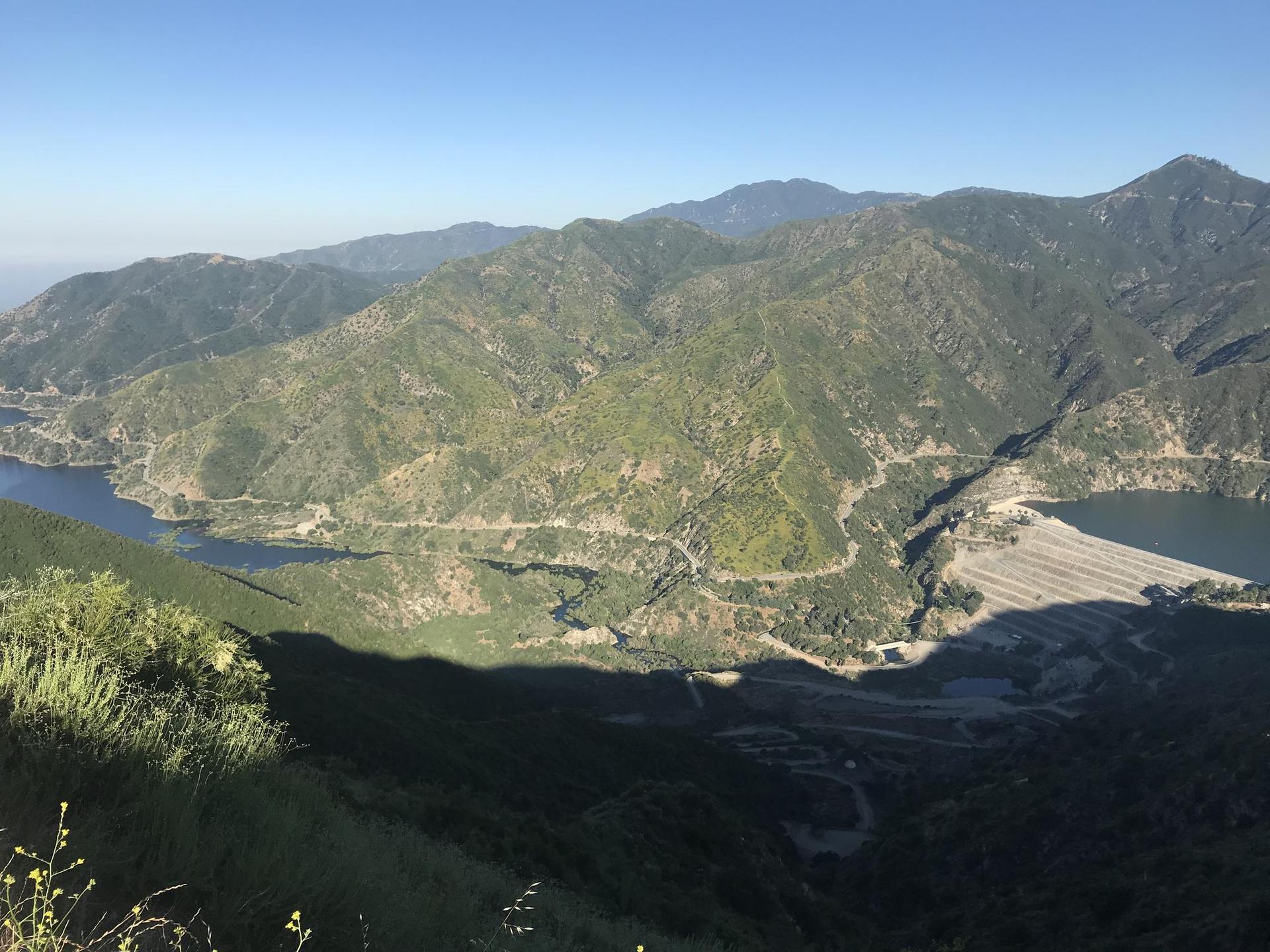 Vast mountainous landscape with a reservoir and dam, bright daylight.