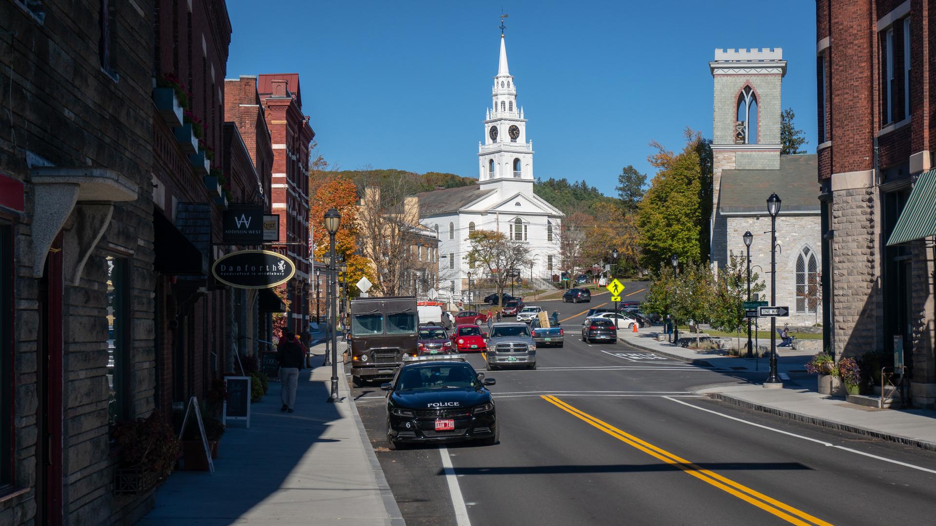 Sunny street scene with cars, historic buildings, and a prominent white church.