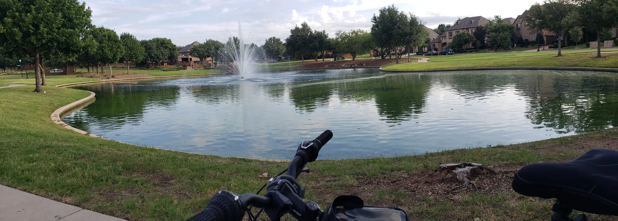Bicycle view of a park pond with a fountain under an overcast sky. - Heritage & Sinclair Park loop