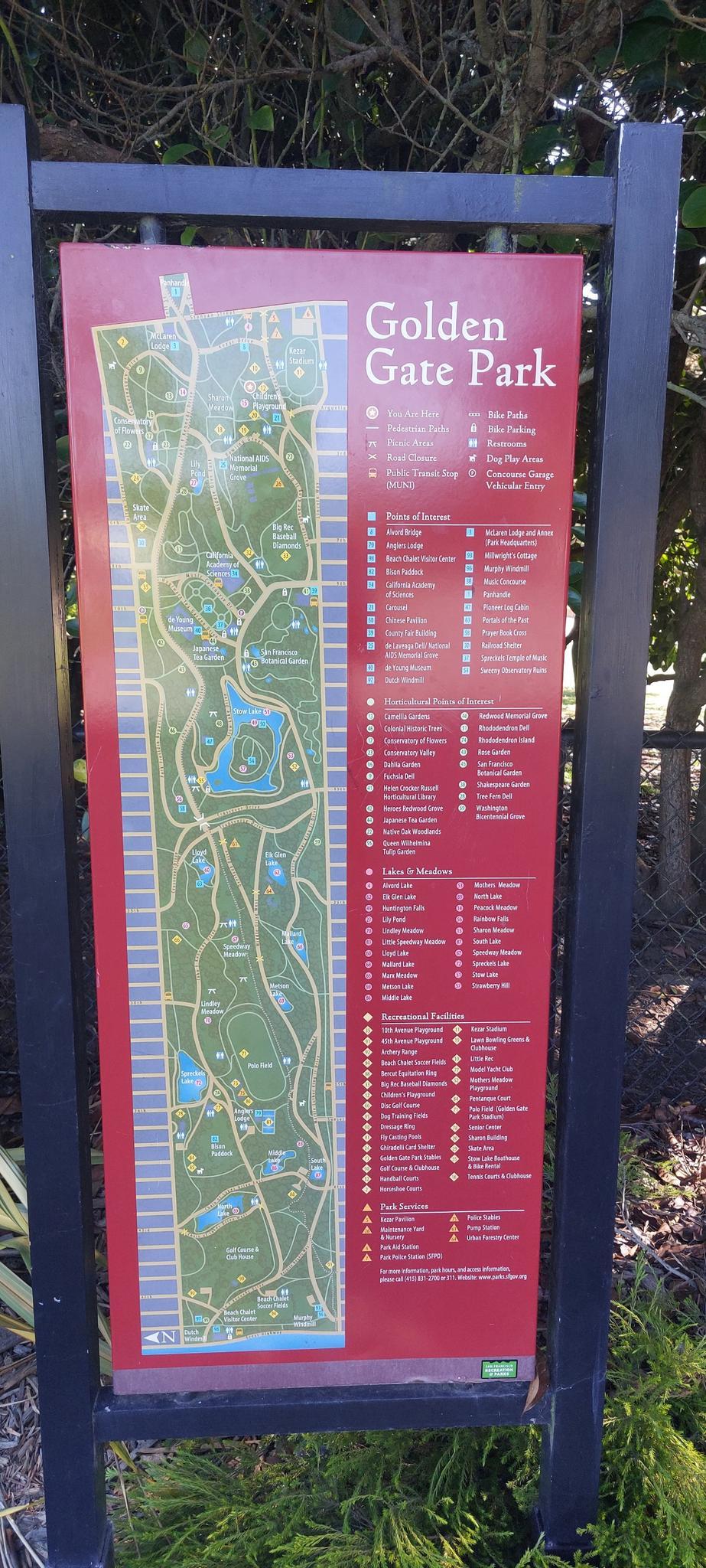 Tall informational sign with a park map and text on a sunny day.