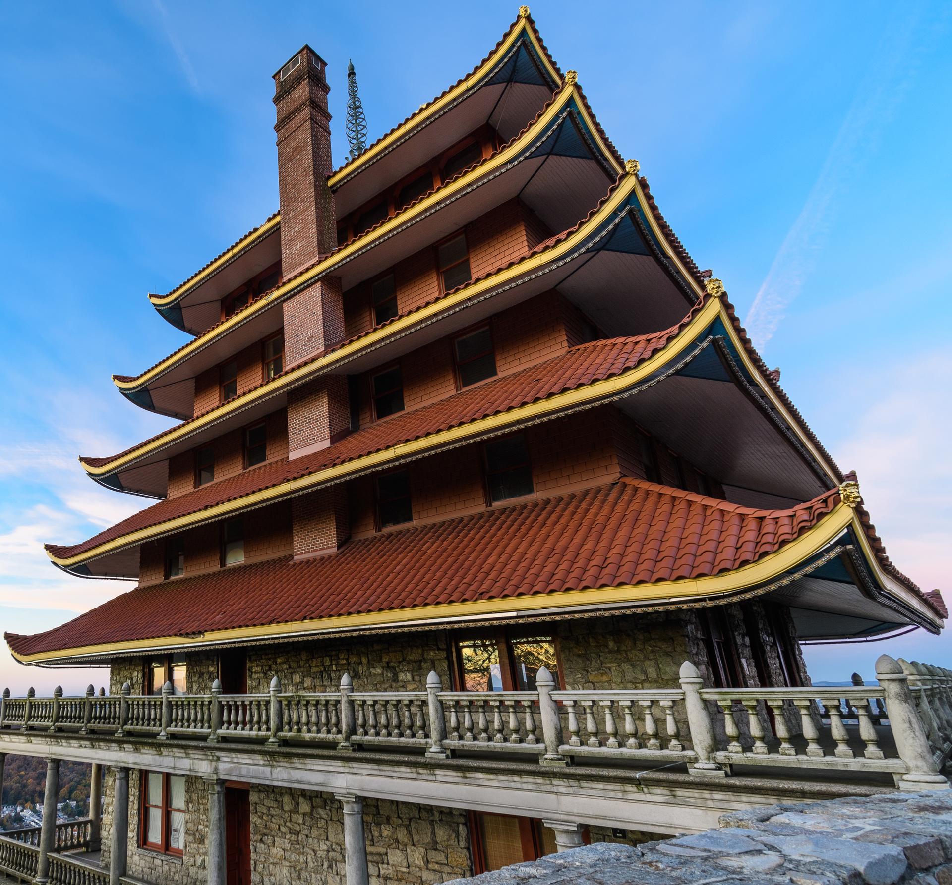 Multi-tiered building with red pagoda roofs and stone balconies under a clear sky.