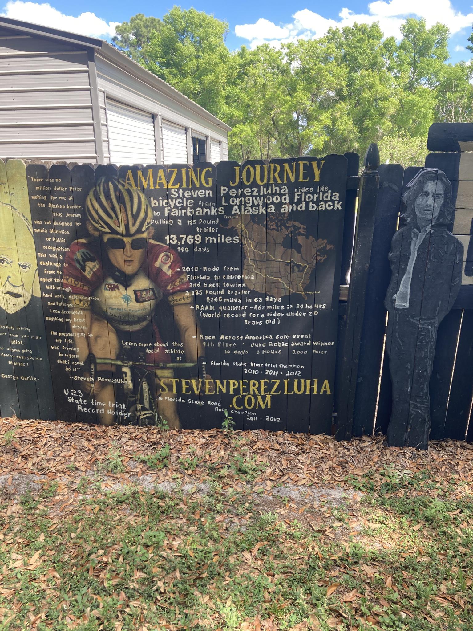 Painted wooden fence with a cyclist mural and journey details.