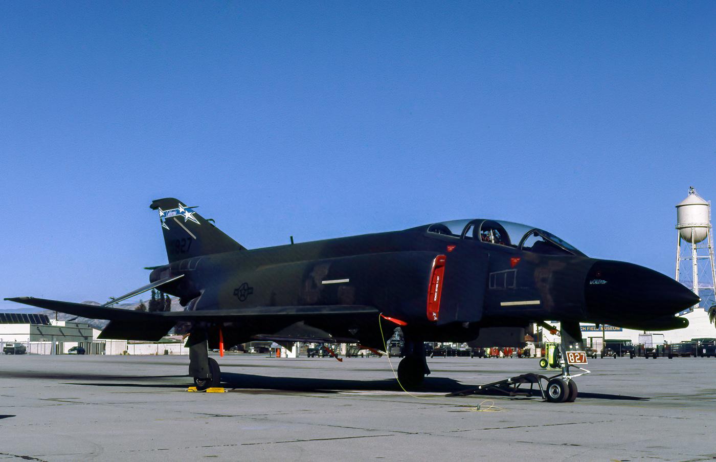 A dark military jet on an airfield, with a water tower in the background.
