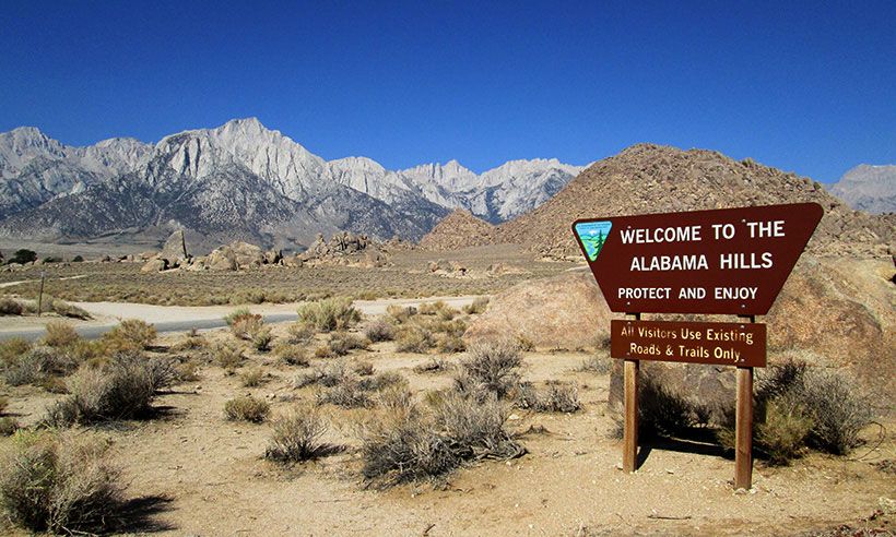 A brown sign stands in a desert landscape with rugged mountains behind it. - Alabama Hills loop — Gravel