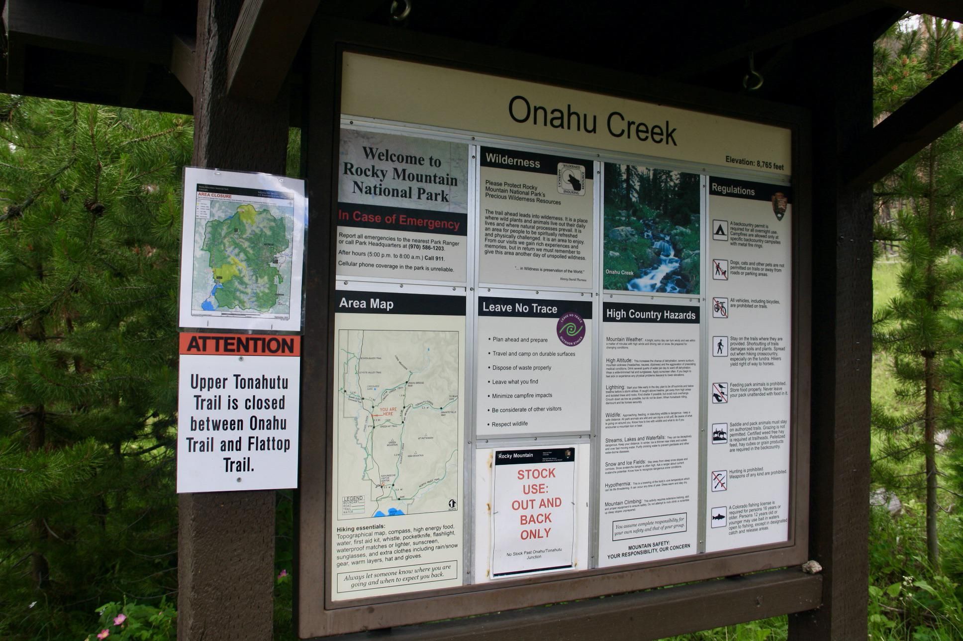 Outdoor information board with maps and text, surrounded by green trees. - Green Mountain and Onahu Creek Trail Loop