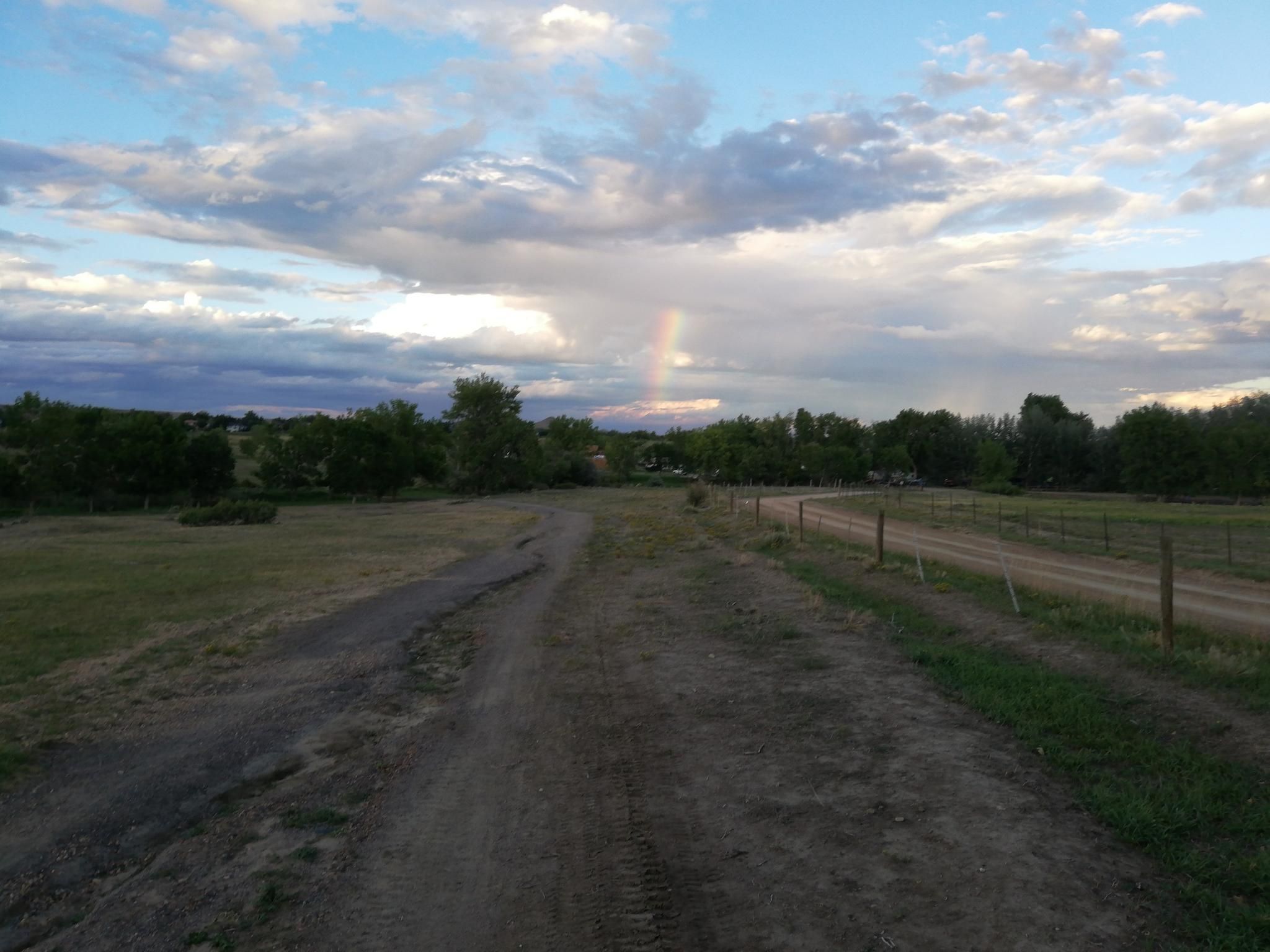 Dirt road through fields with a faint rainbow under a cloudy evening sky. - Eagle, Hidden Valley, and Cobalt Trail Loop