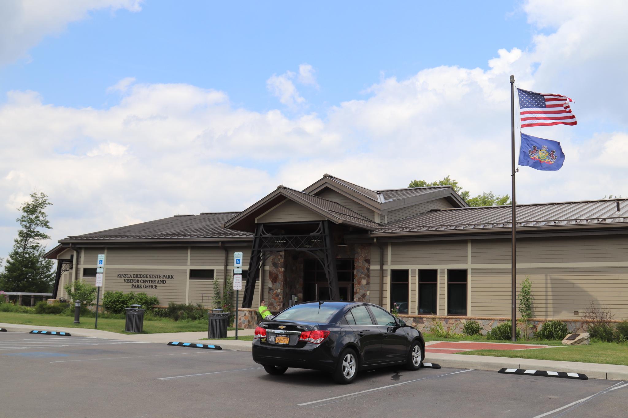 Modern building with flags flying, a black car parked on a sunny day.