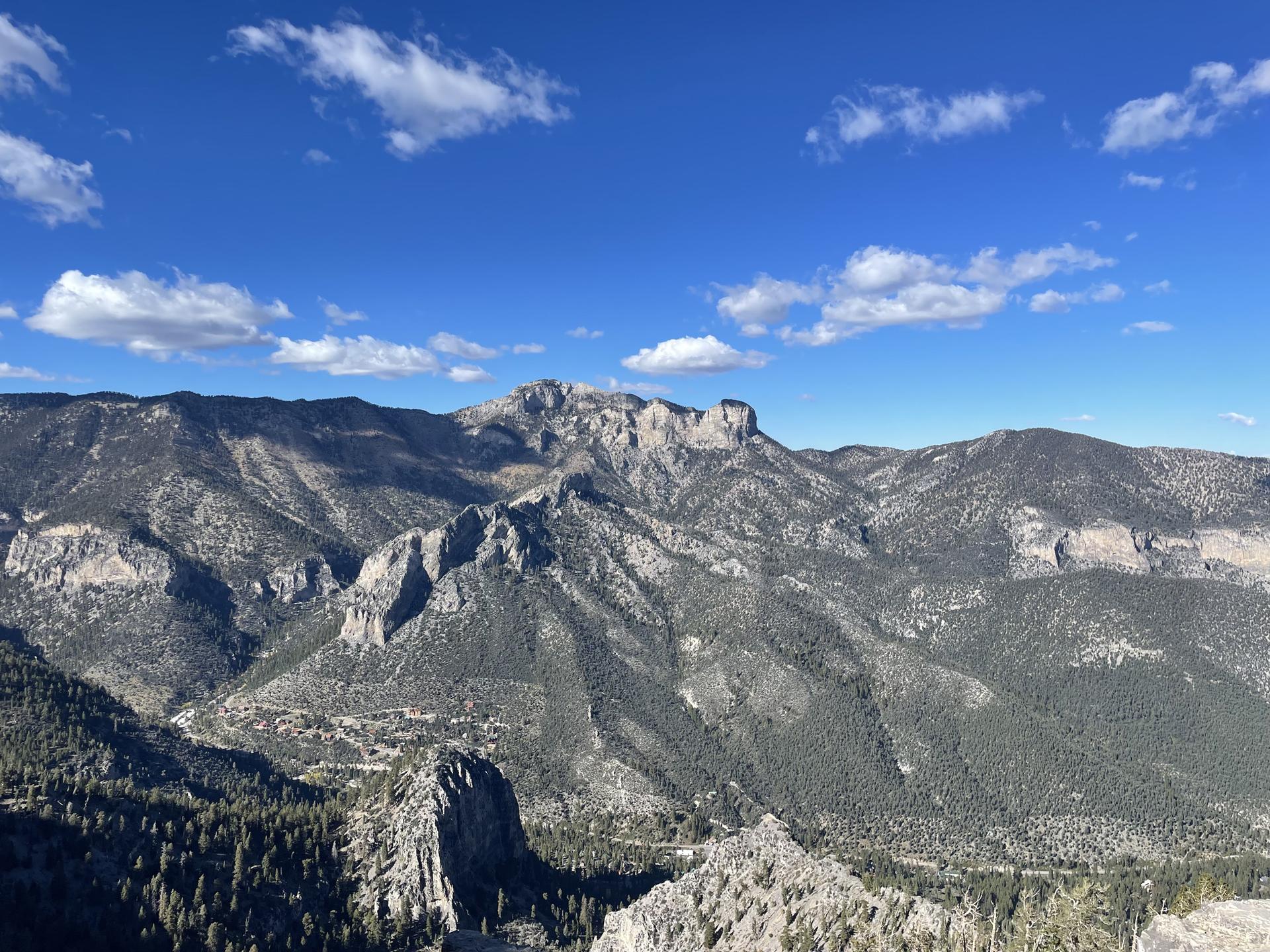 Expansive mountain range with rocky peaks and green slopes under a blue sky.