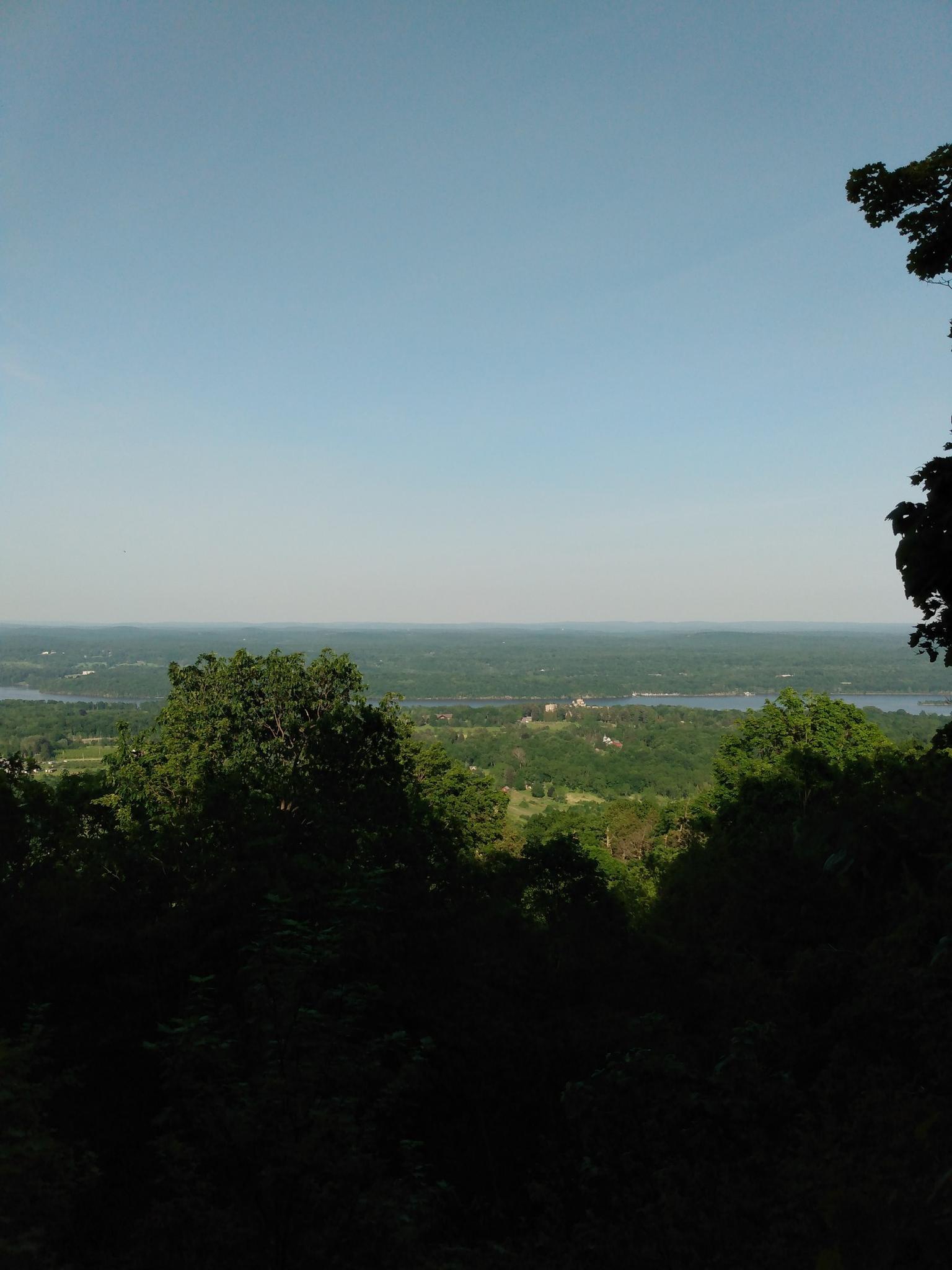 A panoramic view of a distant valley with water bodies under a clear blue sky.
