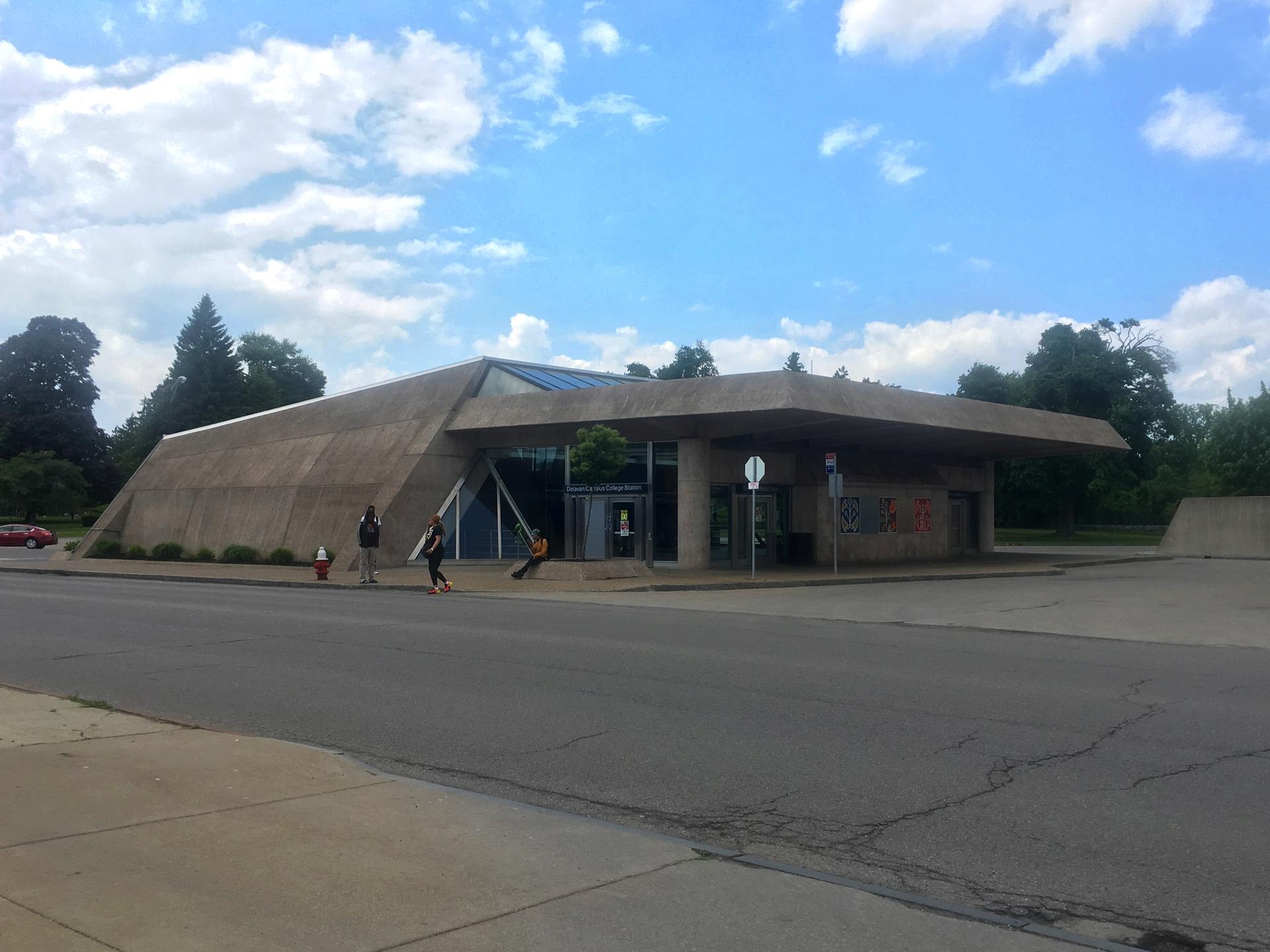 Modern concrete building with a unique roof under a partly cloudy sky.