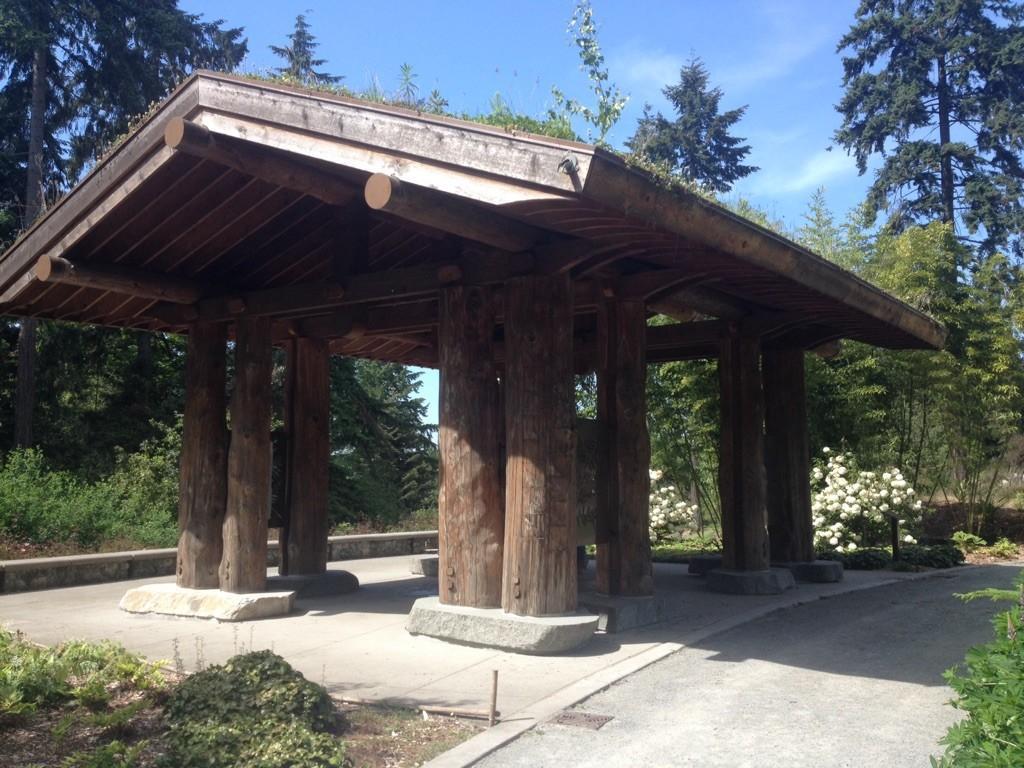 Large wooden pavilion with a green roof on a sunny day.