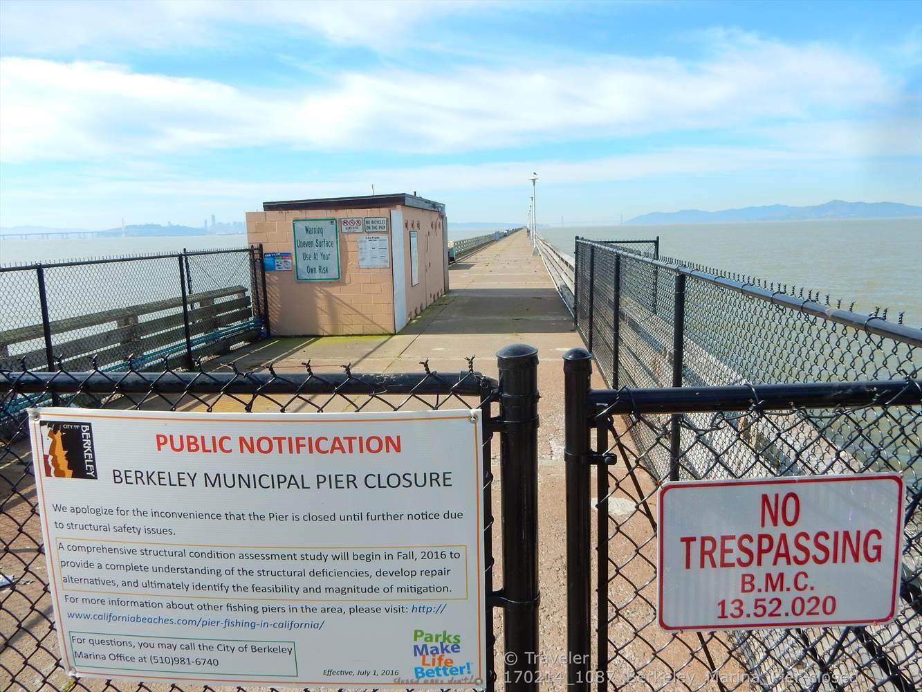 Fenced-off pier entrance with "No Trespassing" sign, extending over water.