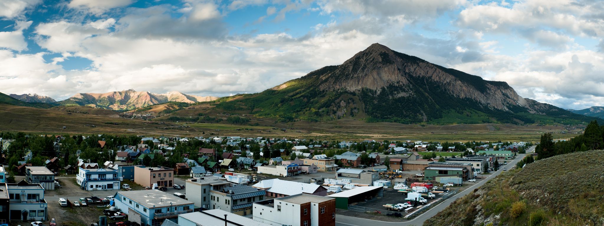 A town nestled in a valley with a large mountain under a cloudy sky. - Green Lake Trail