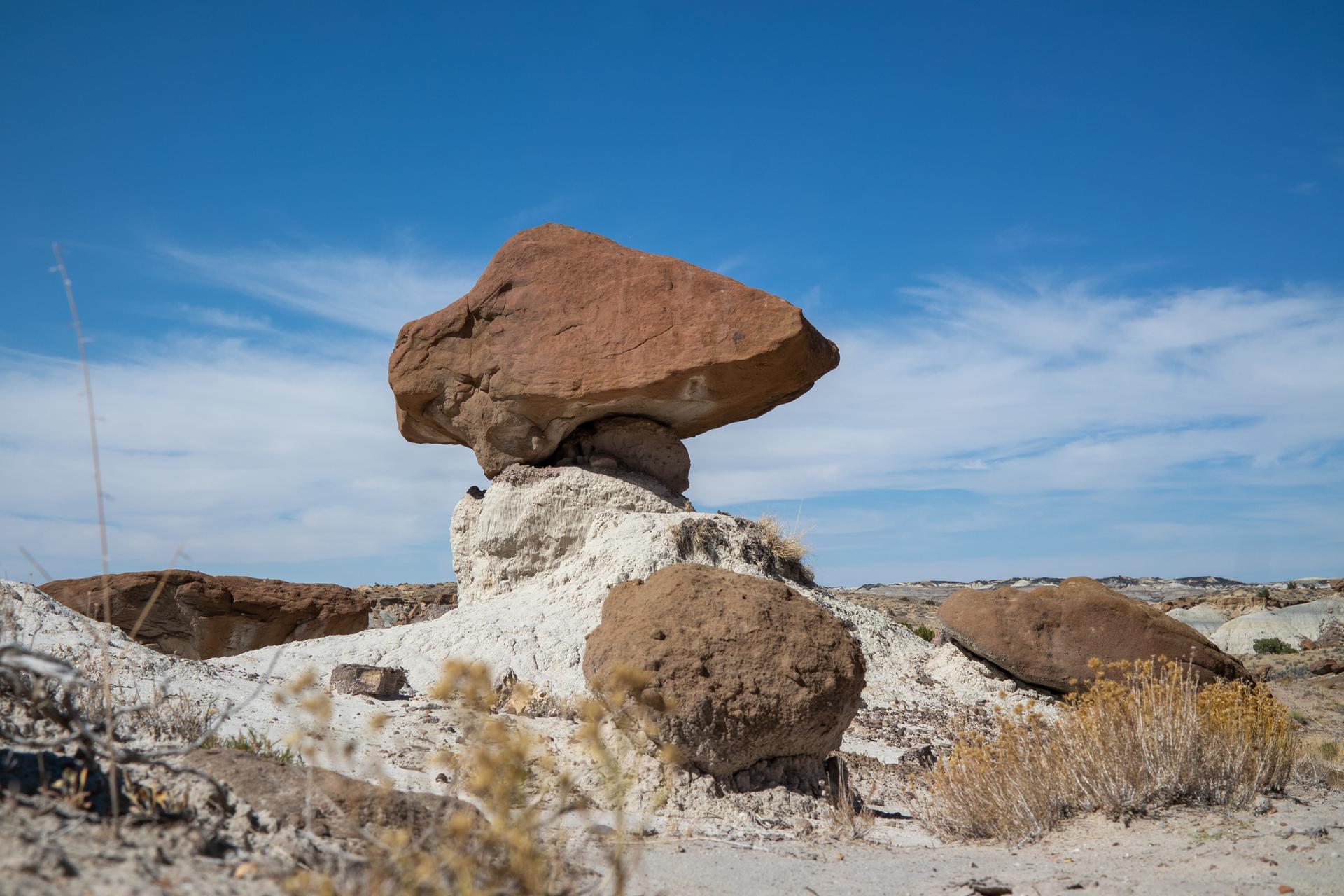 Large balanced rock formation in a desert landscape under a clear blue sky.