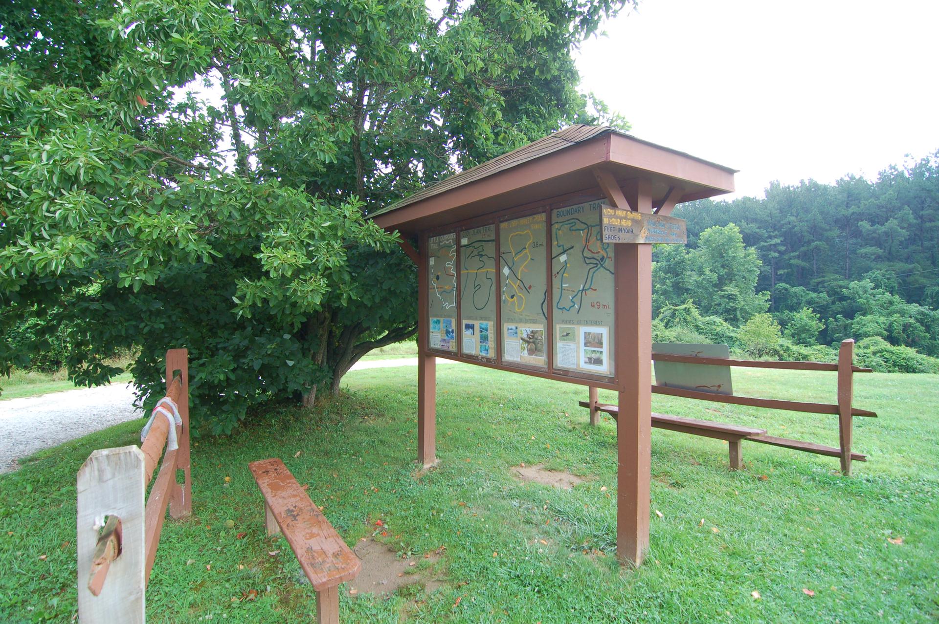 An outdoor information kiosk with maps stands in a grassy park.