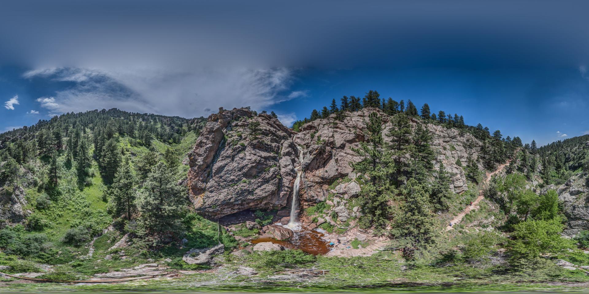 Panoramic view of a waterfall plunging between rocky cliffs and green forests.