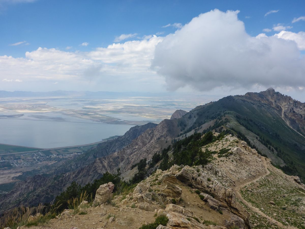 Rocky mountain ridge with a path, overlooking a vast lake under clouds. - Ben Lomond Trail