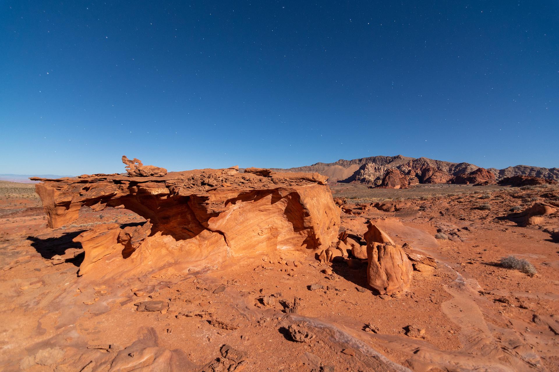 Layered red rock formation under a dark blue, star-filled night sky.