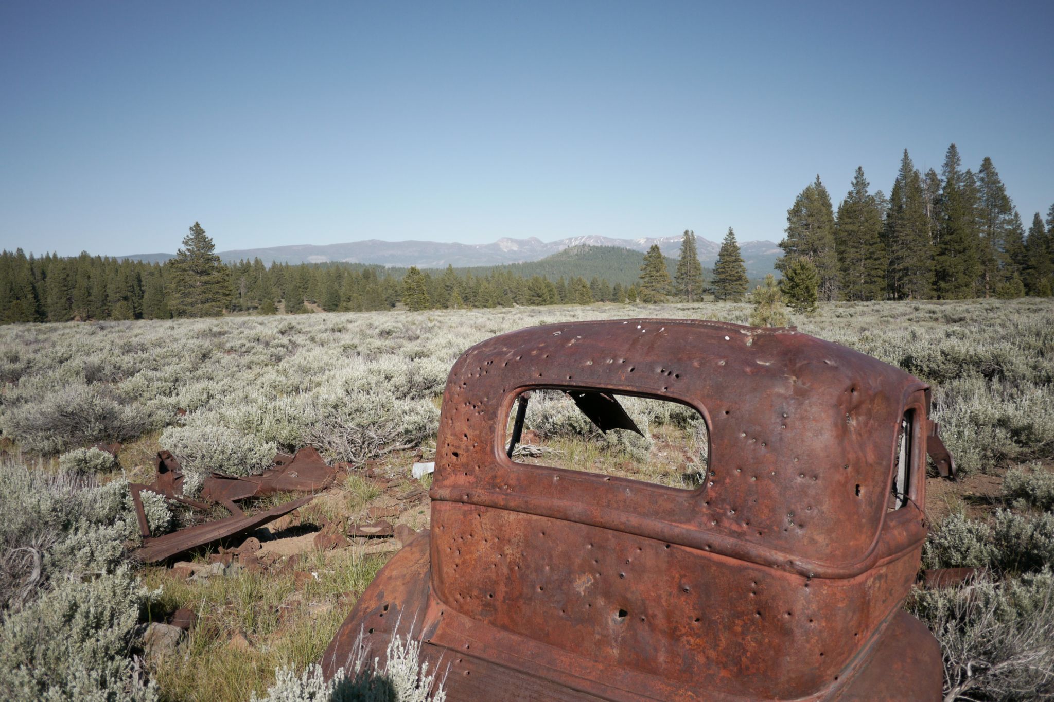 Rusted old car body in a dry, sunny field with distant mountains. - Prosser & Alder Creek loop