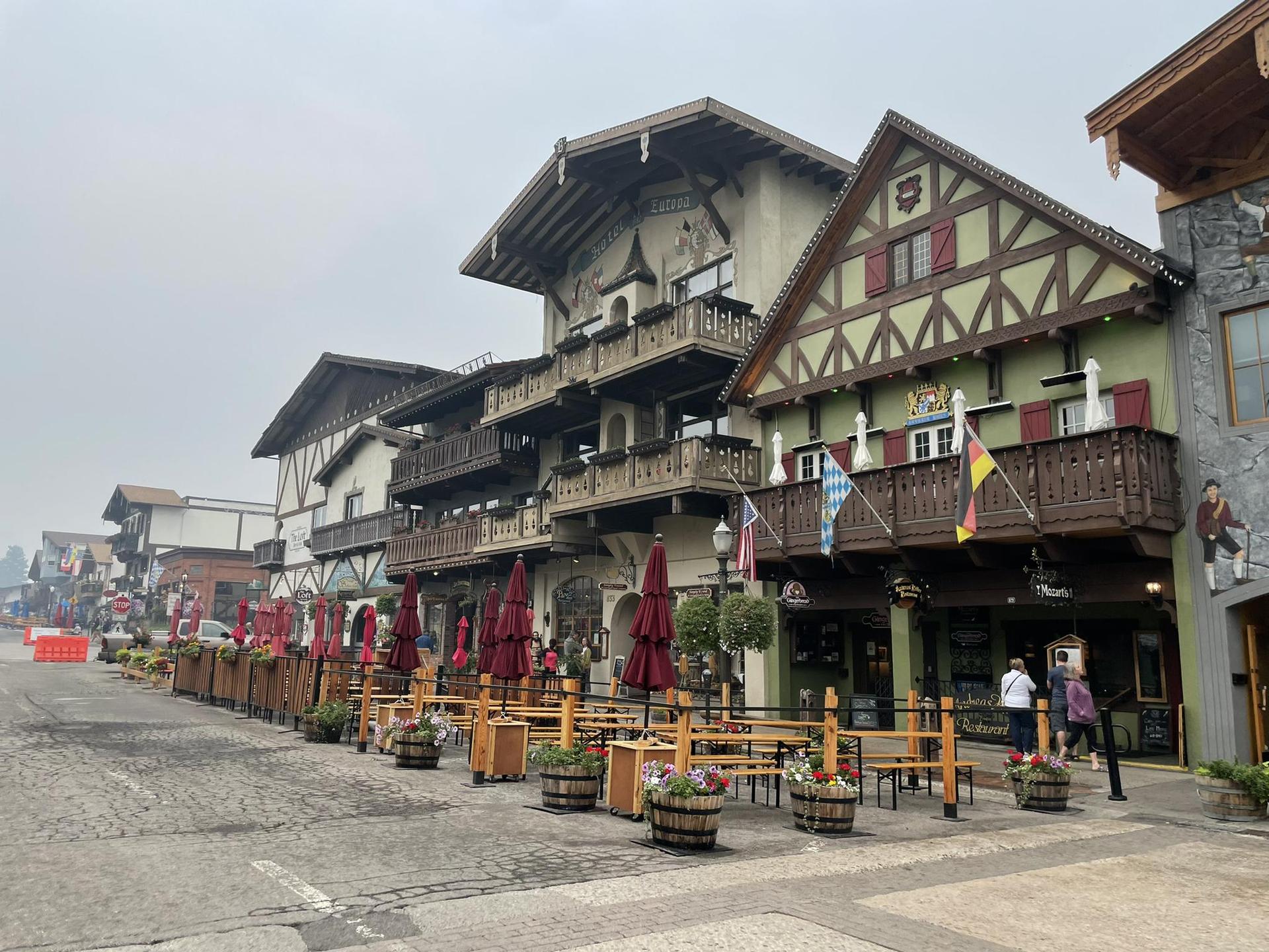 European-style buildings with outdoor dining areas and a few people on a cloudy day.