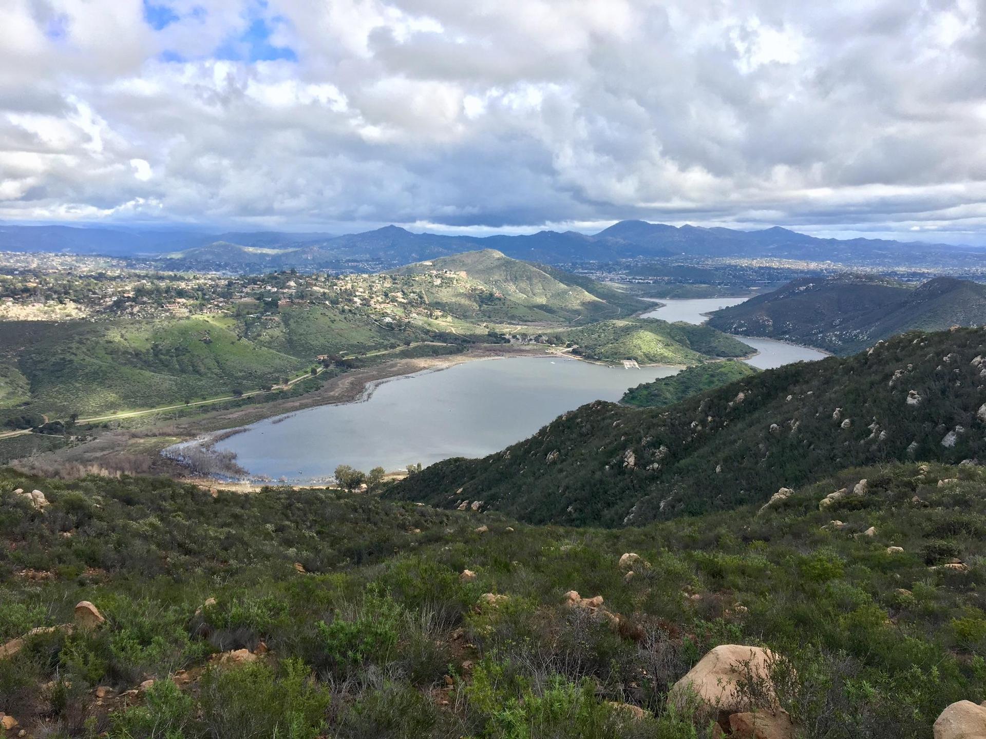 Panoramic view of multiple lakes and green rolling hills under a cloudy sky.