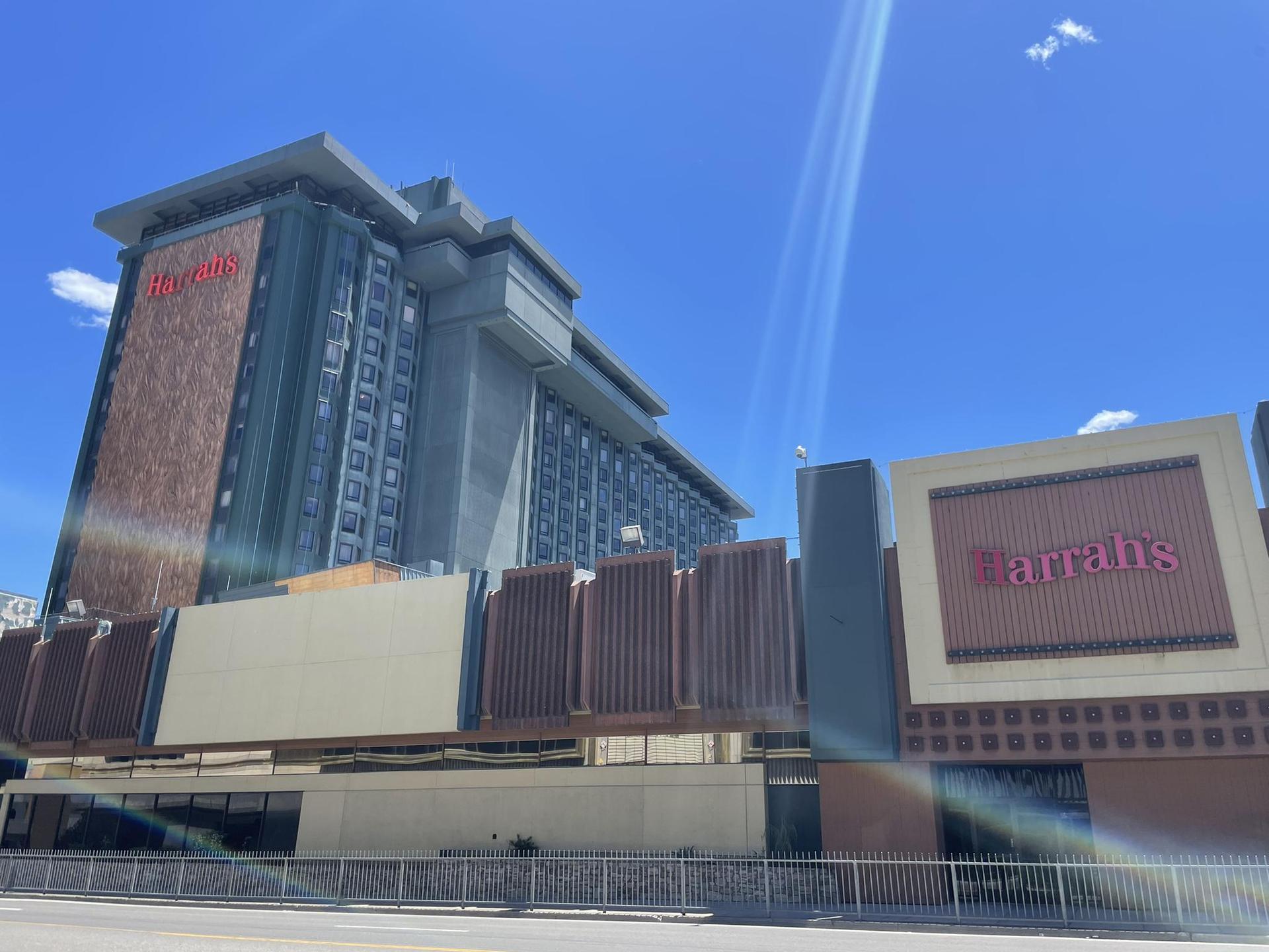Tall hotel building with "Harrah's" sign under a bright blue sky.