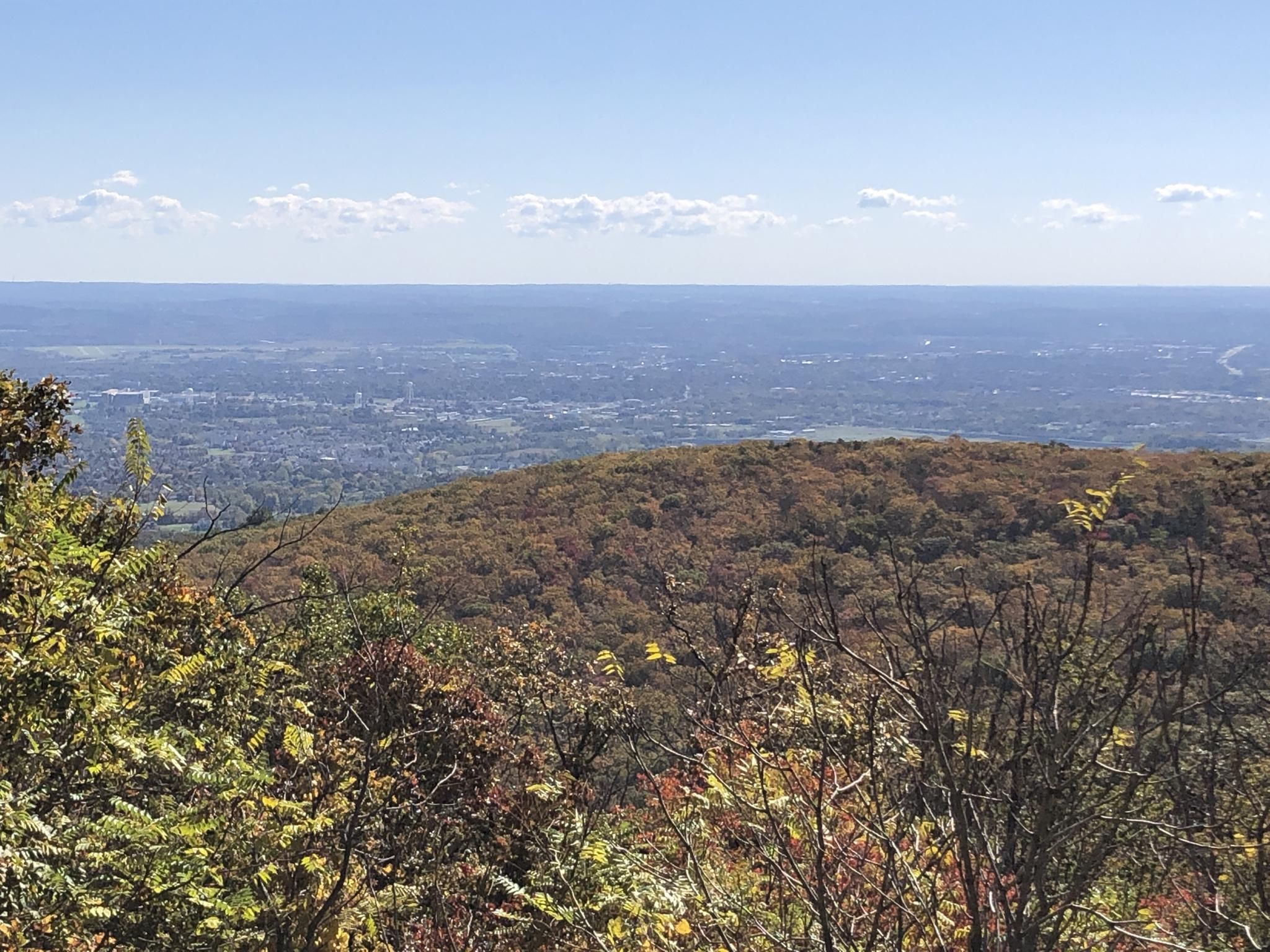 Expansive view of a town nestled among autumn-colored hills under a blue sky. - Gambrill State Park loop
