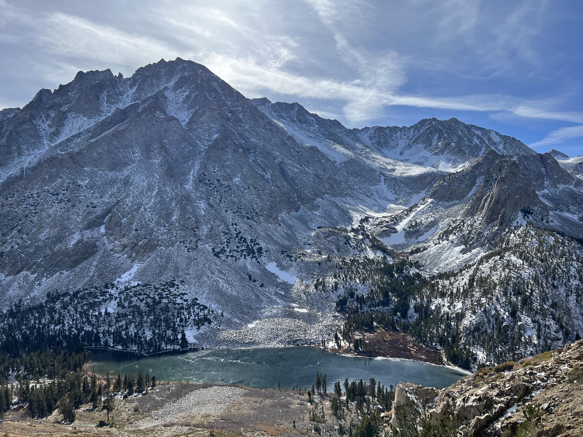 Majestic snow-dusted mountains towering over a deep blue alpine lake.