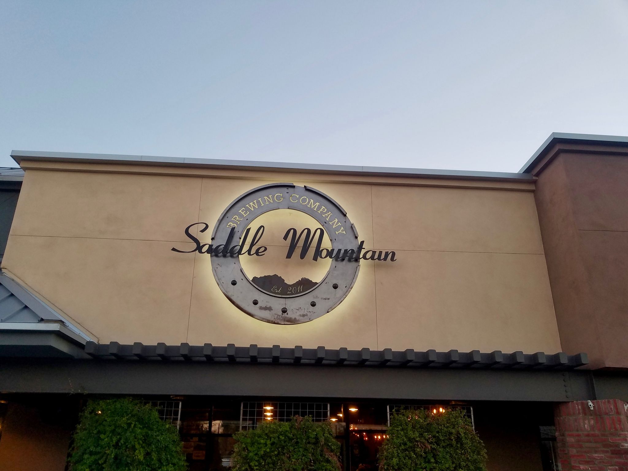 Illuminated "Saddle Mountain Brewing Company" sign on a building facade at dusk. - Bullard Wash Park & Roosevelt Canal loop