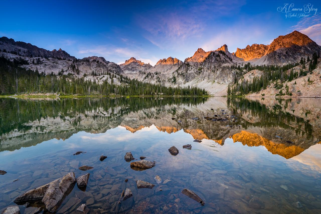 Stunning lake reflecting jagged mountains bathed in golden light.