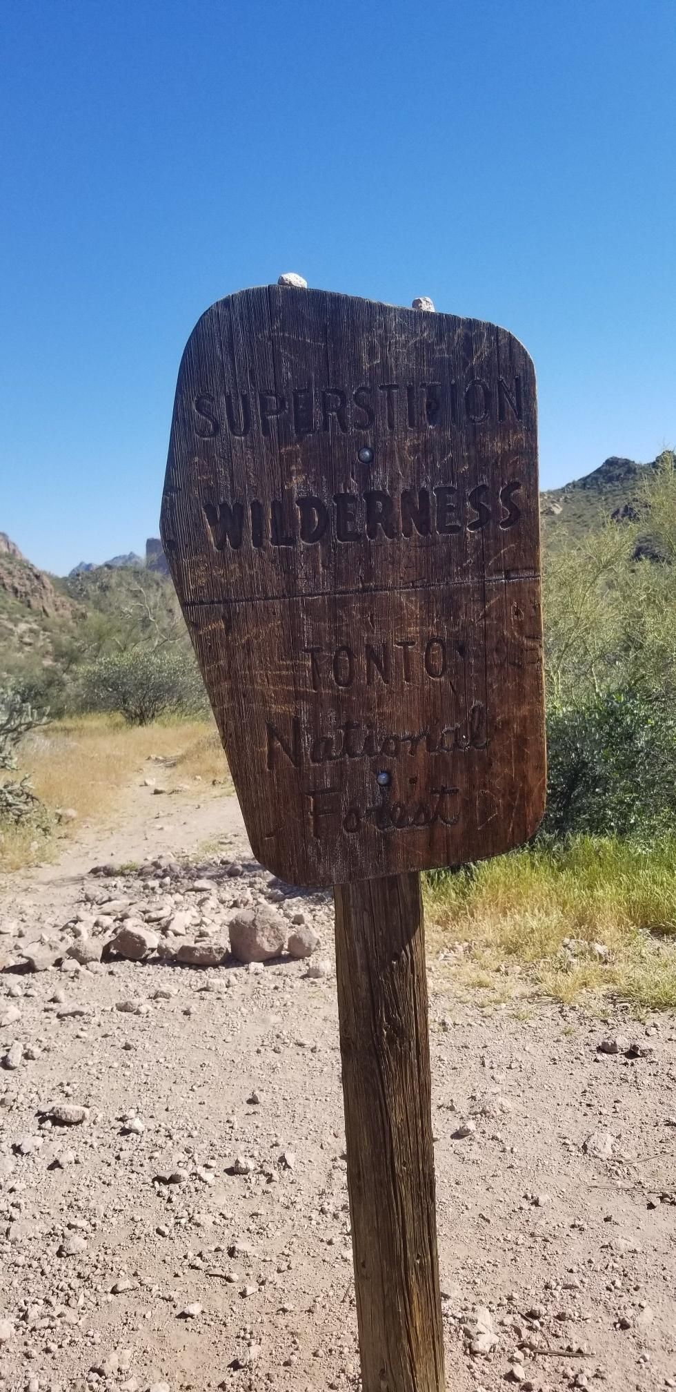 Weathered wooden sign on a post in a rocky, arid landscape. - Boulder Canyon Trail #103