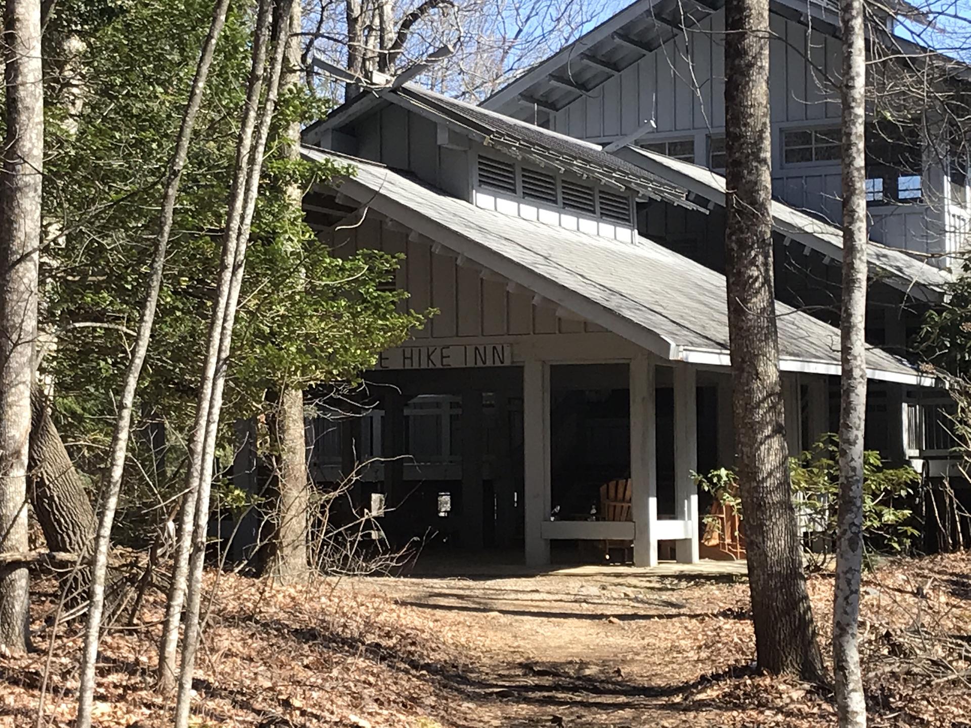 A rustic wooden building entrance with a covered porch, surrounded by trees.