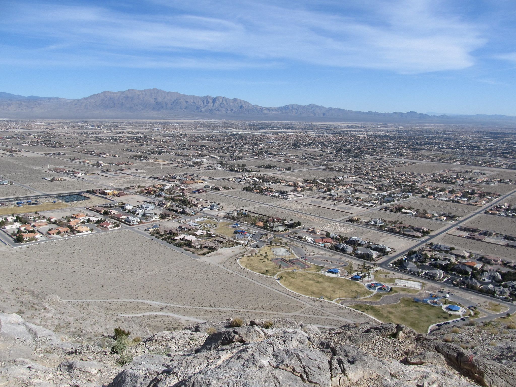 Aerial view of a sprawling desert city under a clear sky with distant mountains. - Lone Mountain Loop
