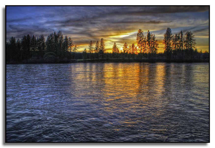 Wide river reflecting a vibrant sunset behind silhouetted trees. - Knothead Loop Trail