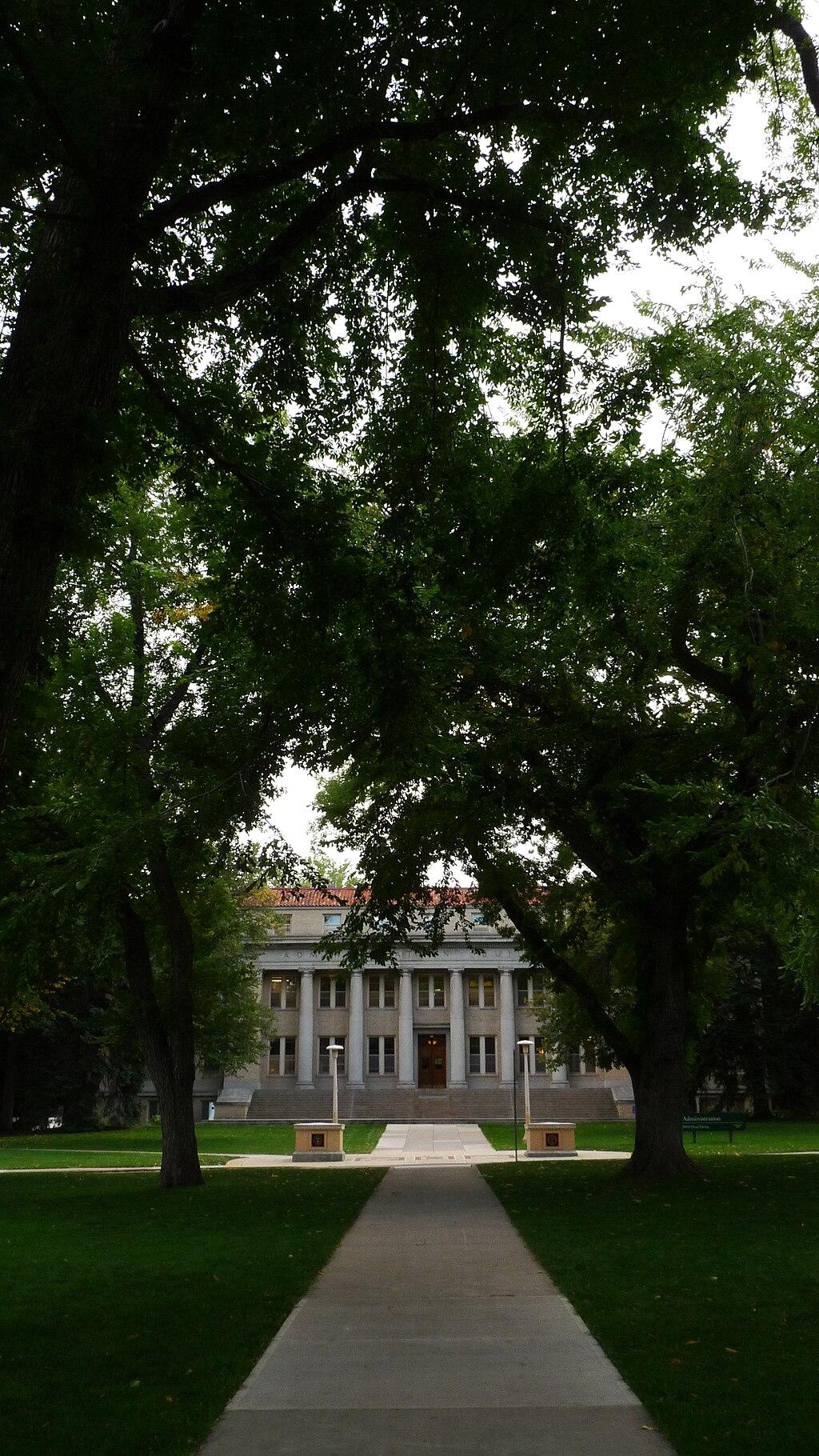 A symmetrical path leads to a grand building framed by tall trees.