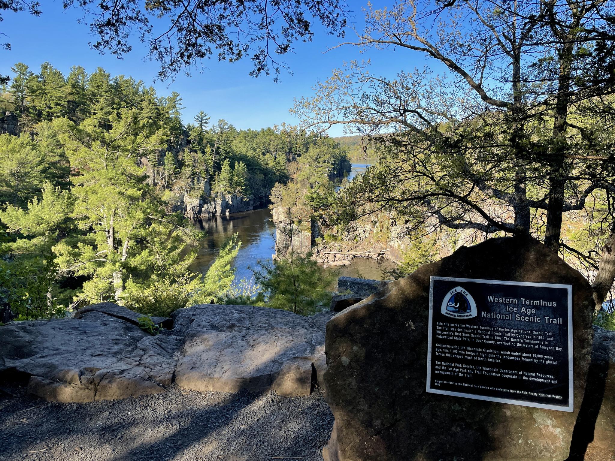 A river flows through a rocky gorge under a bright blue sky.