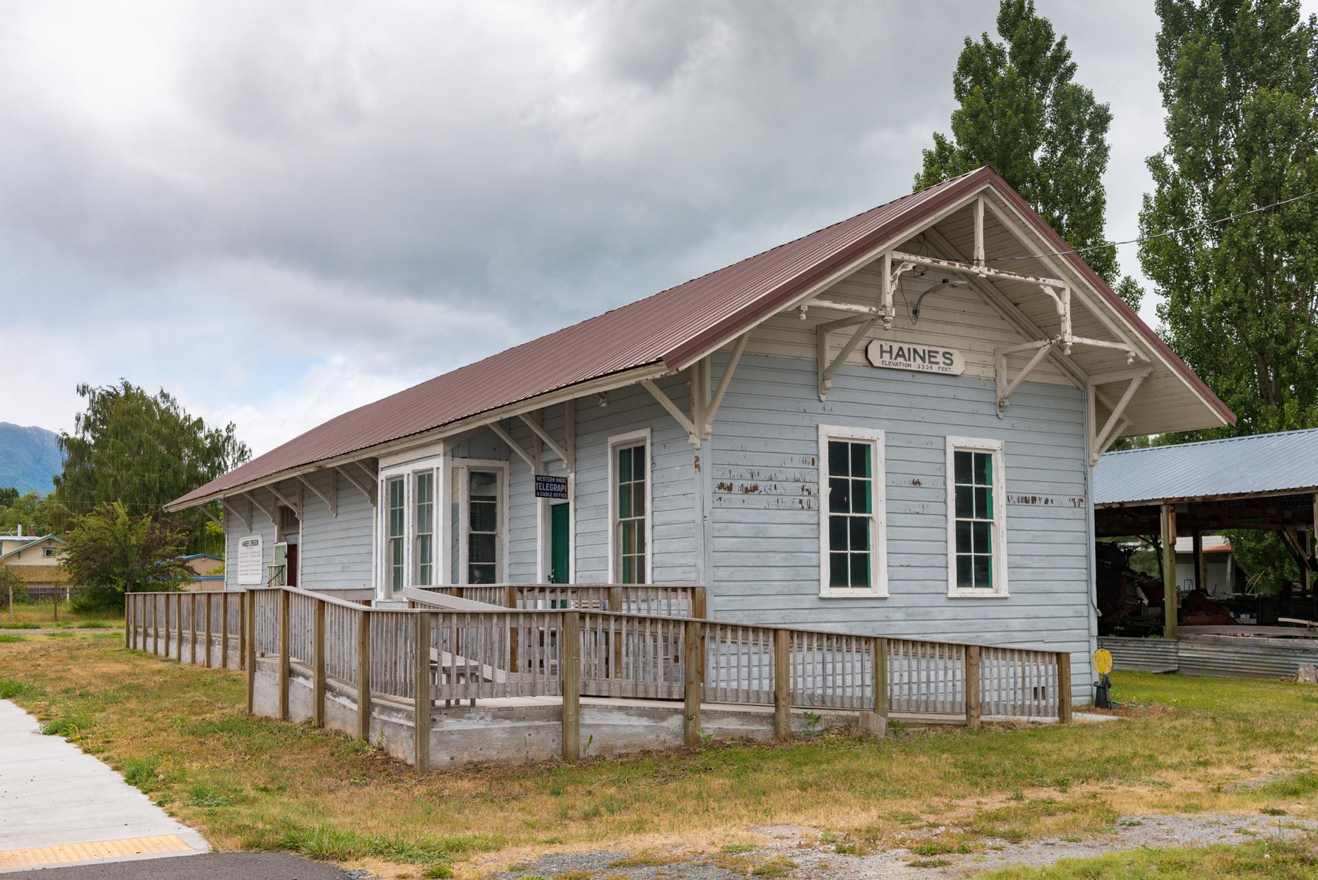 Historic light blue building with a red roof under an overcast sky.
