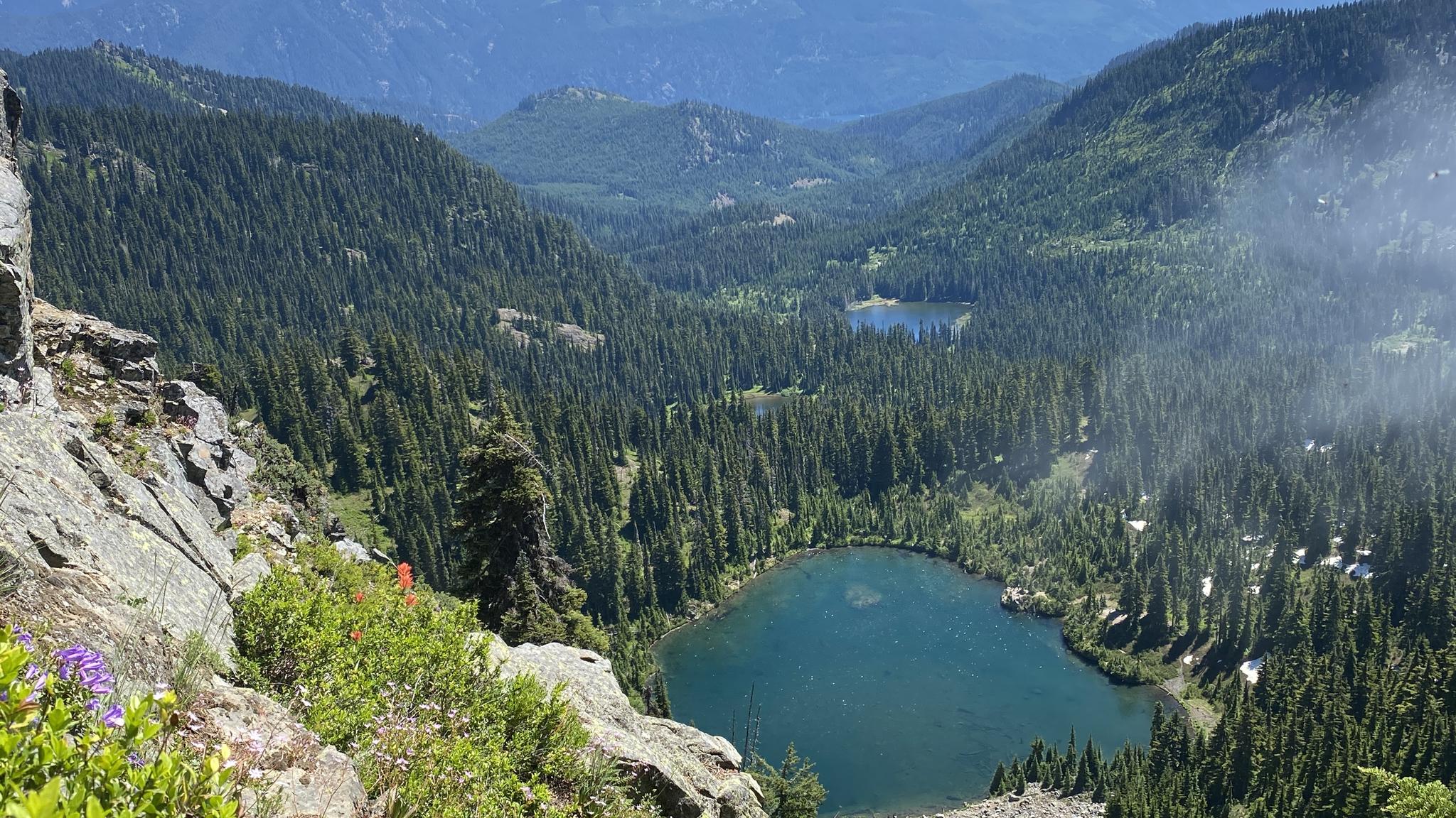 Two serene blue mountain lakes nestled in a vast green forest valley.