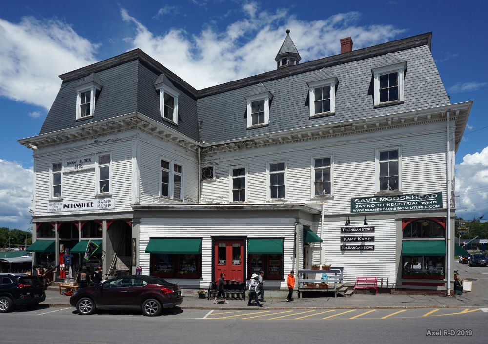 Large white building with shops under a bright, cloudy sky, people walking. - Greenville to Rockwood