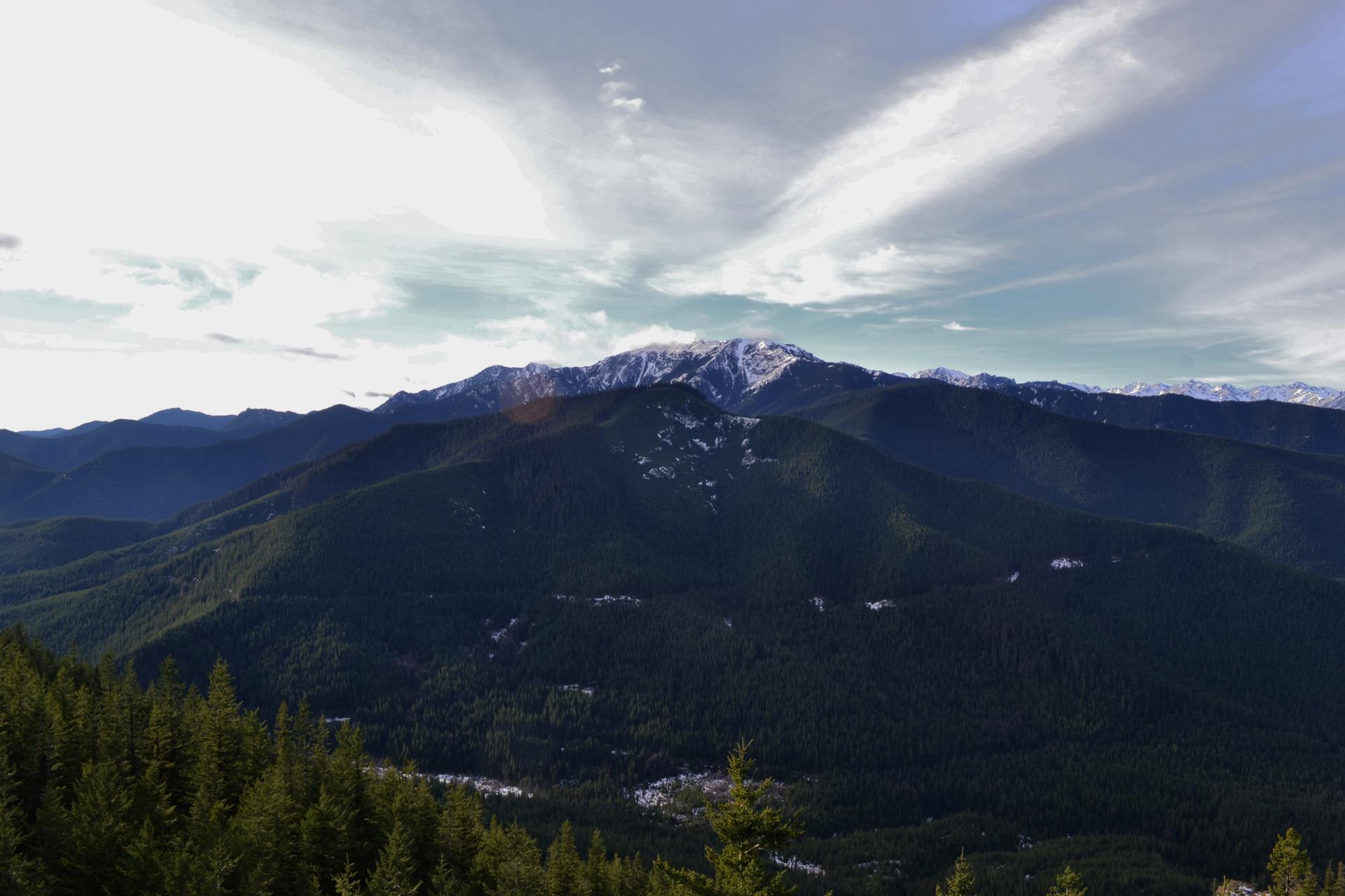 Expansive view of forested mountains under a dramatic cloudy sky.
