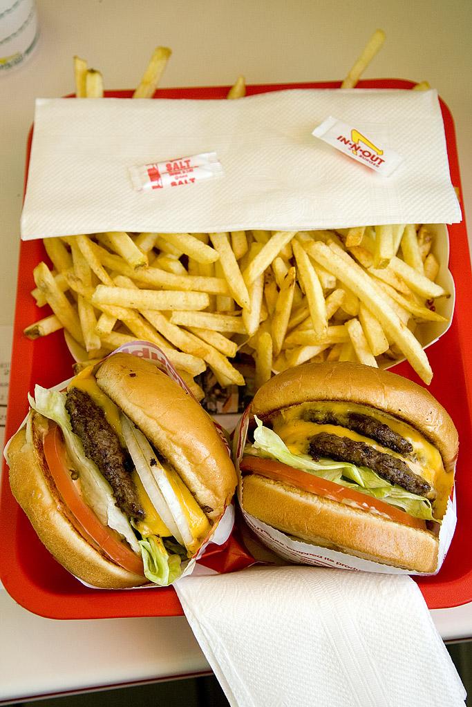 Two cheeseburgers and a large order of french fries on a red tray.