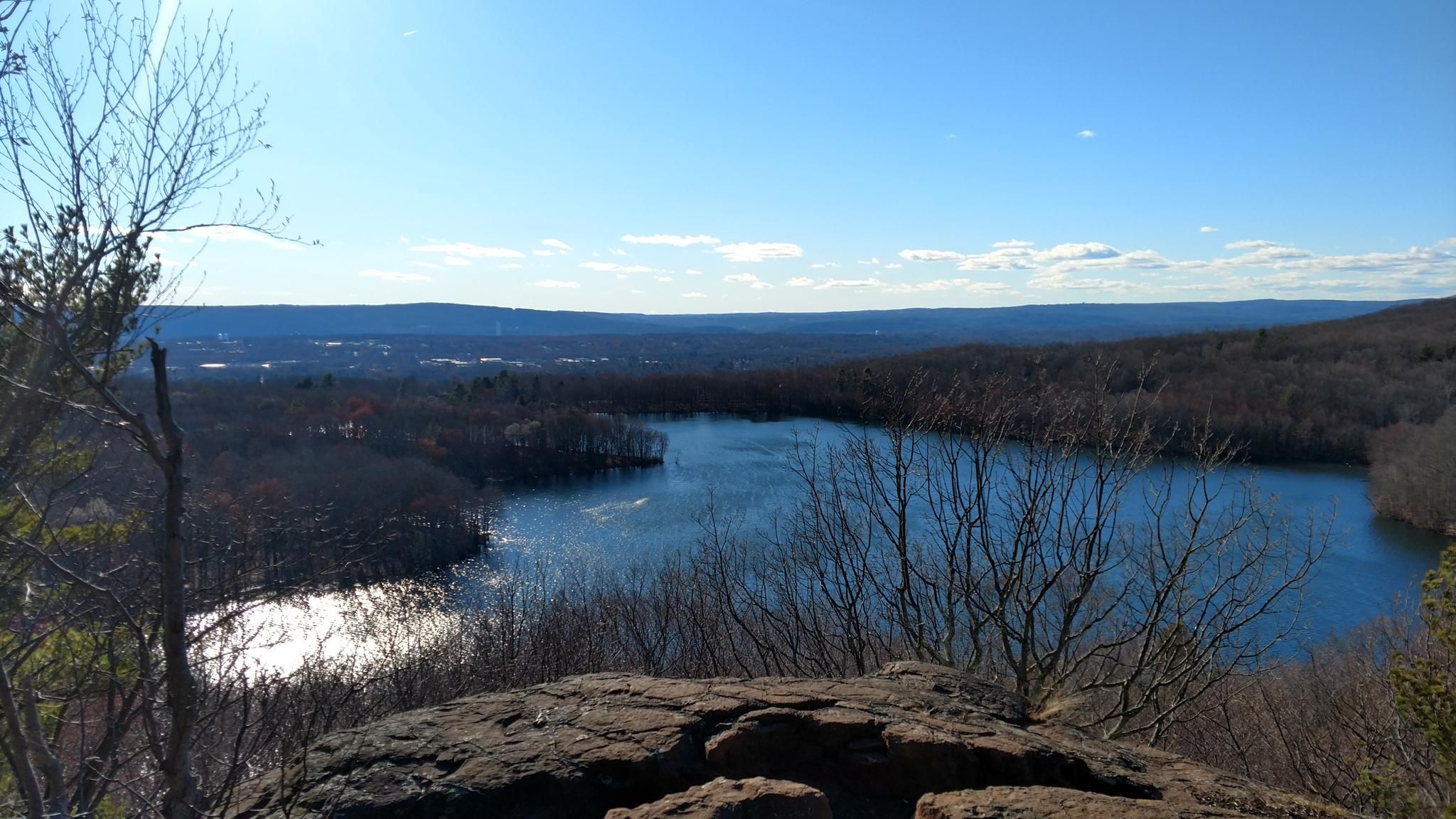 Sunny overlook of a blue lake surrounded by vast, bare forest. - Crescent Lake and Metacomet Trail Loop