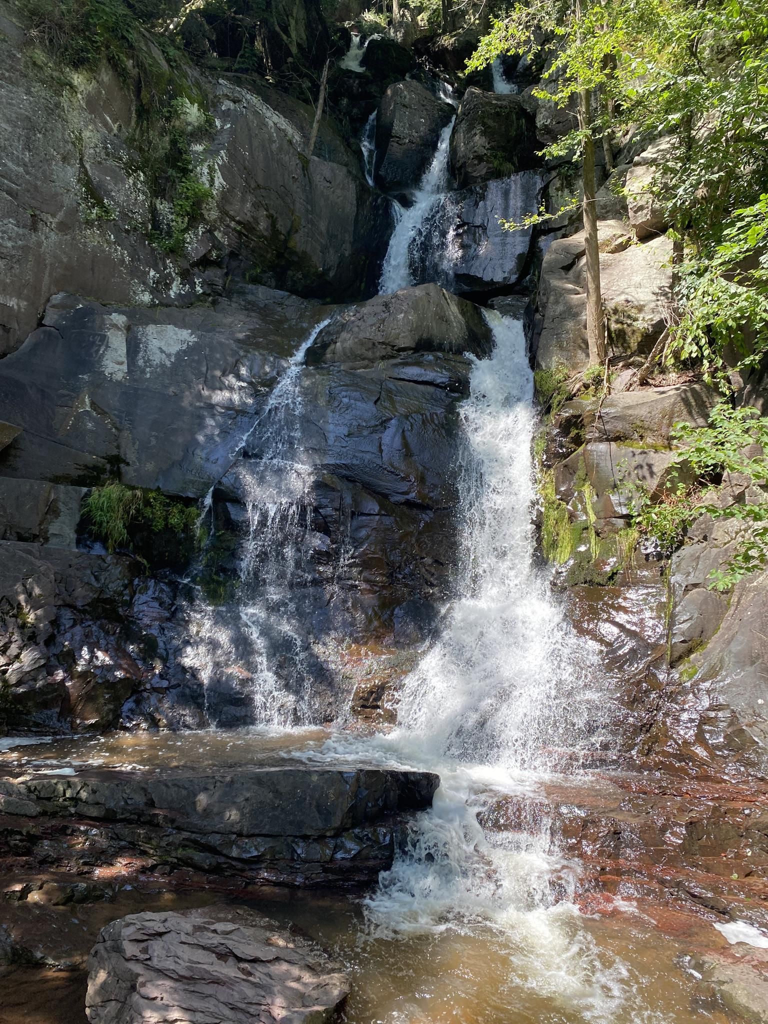 A multi-tiered waterfall cascades down a rocky cliff in bright sunlight. - D&L Trail: White Haven to Jim Thorpe