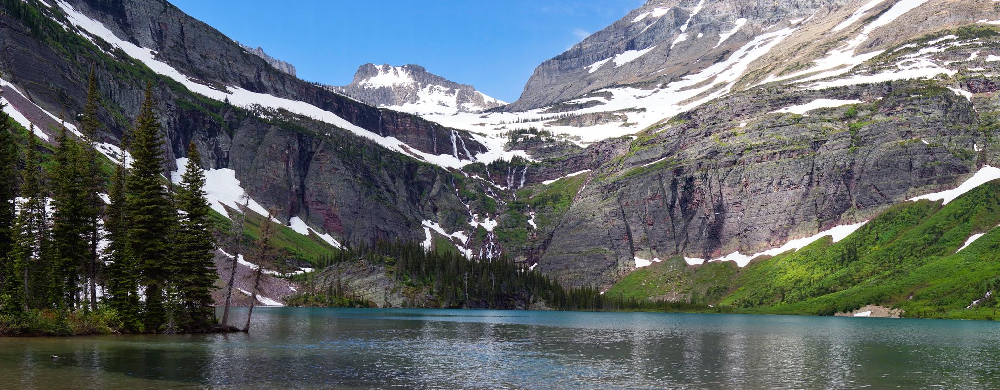 A turquoise mountain lake surrounded by snow-dusted peaks on a bright day.